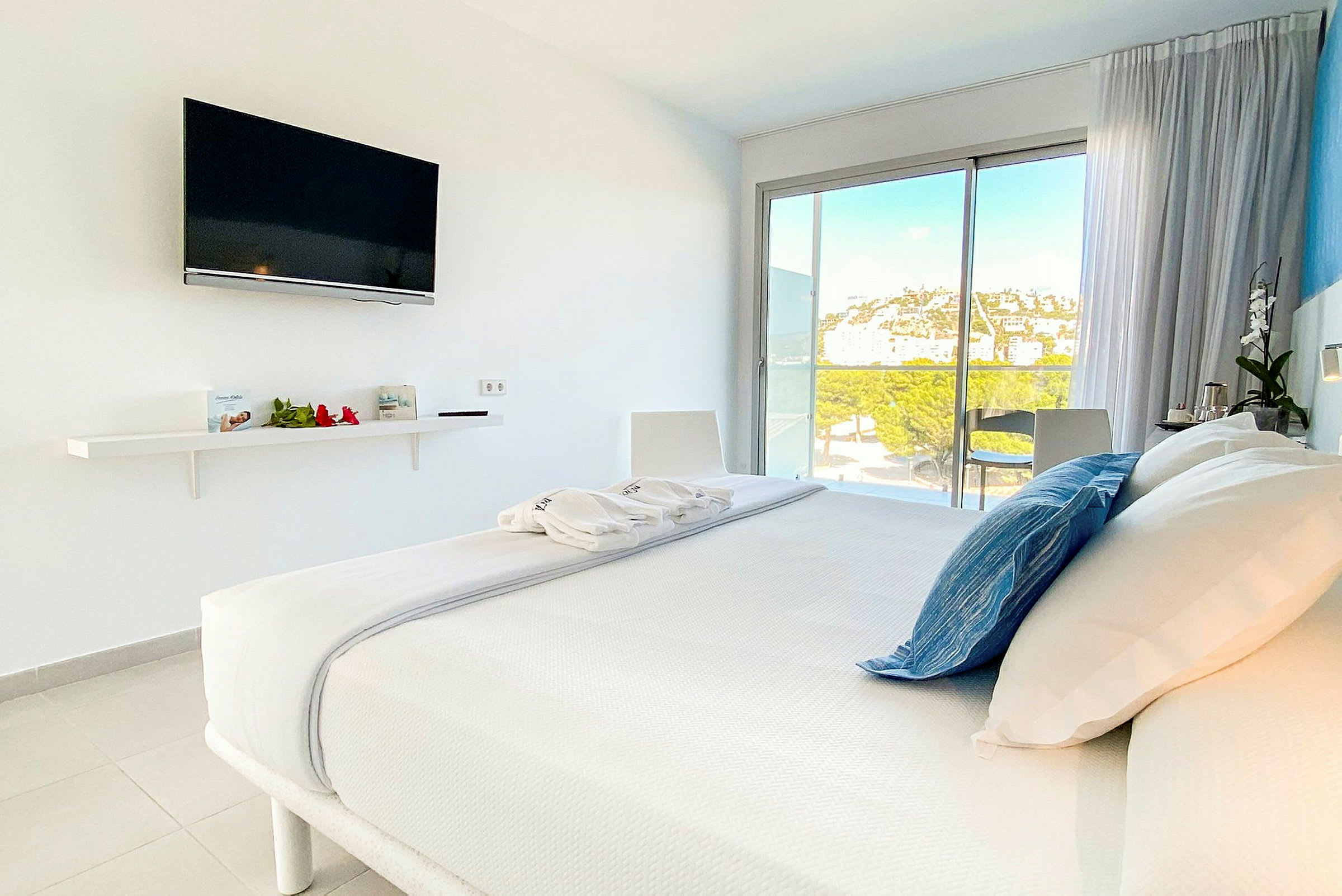 Ett modernt hotellrum med en dubbelsäng och en TV på väggen. Rummet har stora fönster med utsikt över landskapet. (AI-genererad text)