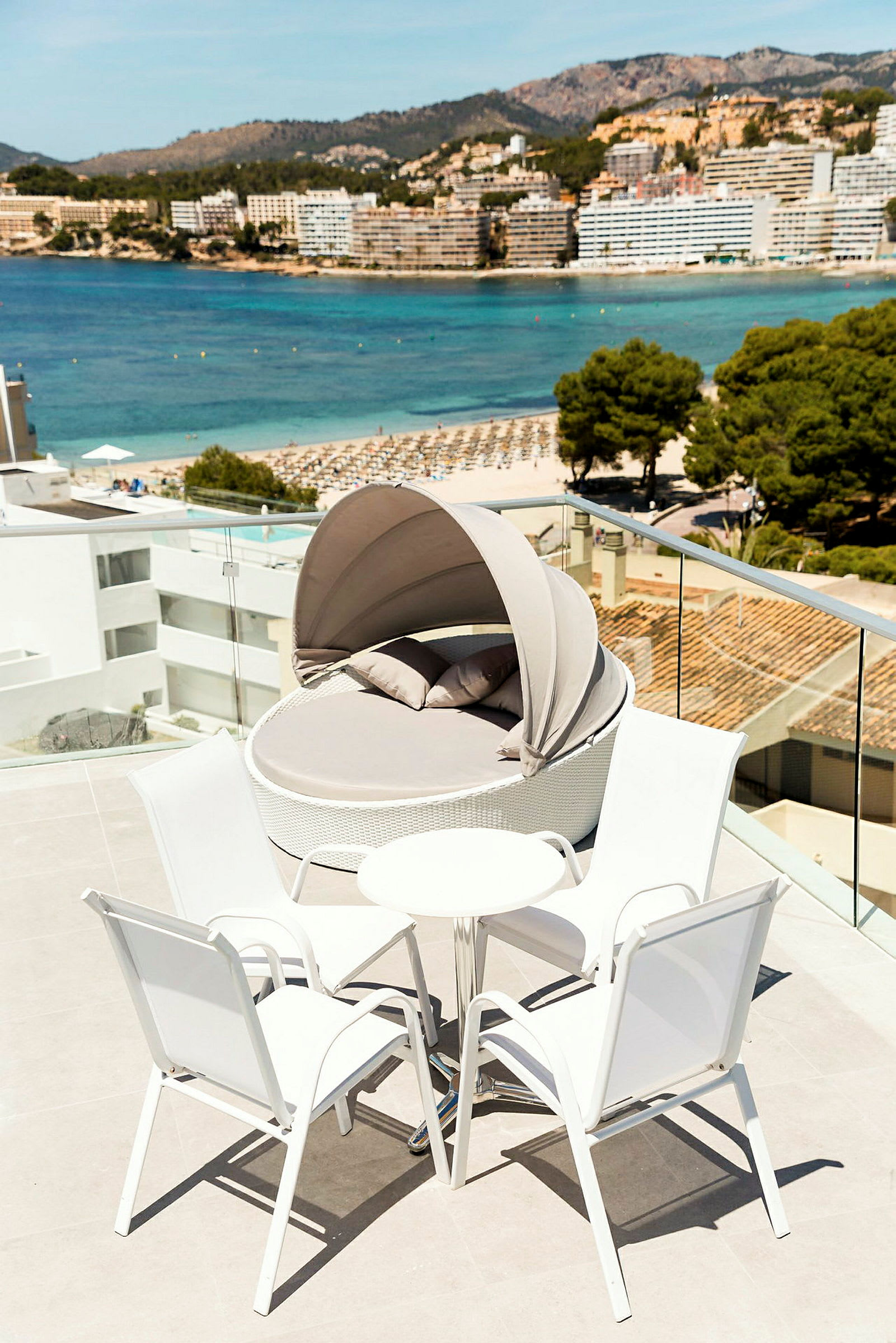 Terrass med vit sitthörna och solsäng i en modern semesteranläggning med utsikt över stranden och havet. (AI-genererad text)