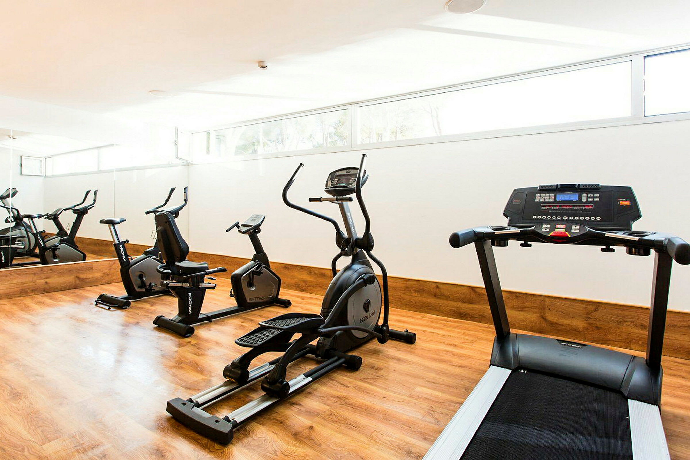 Ett gymrum med träningsutrustning, inklusive löpband, motionscyklar och crosstrainer. (AI-genererad text)