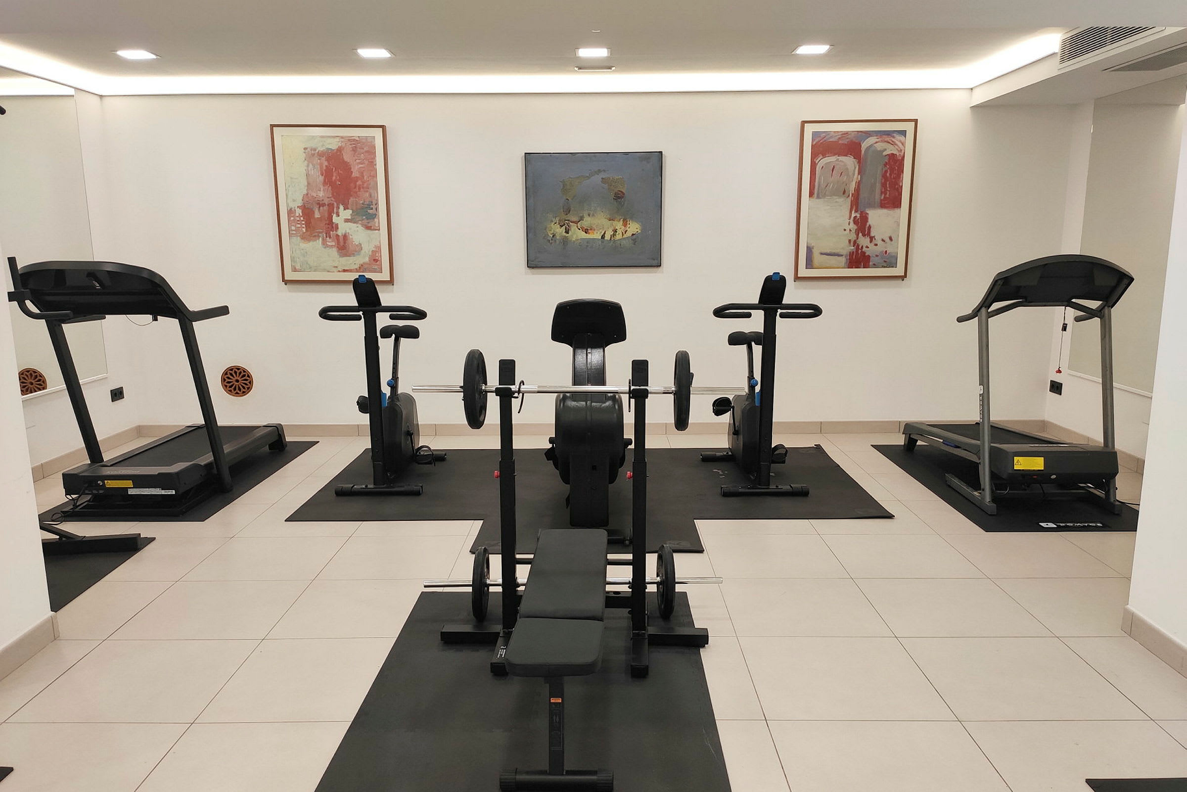 Ett gym med träningsutrustning som löpband, motionscyklar och en bänkpress. (AI-genererad text)