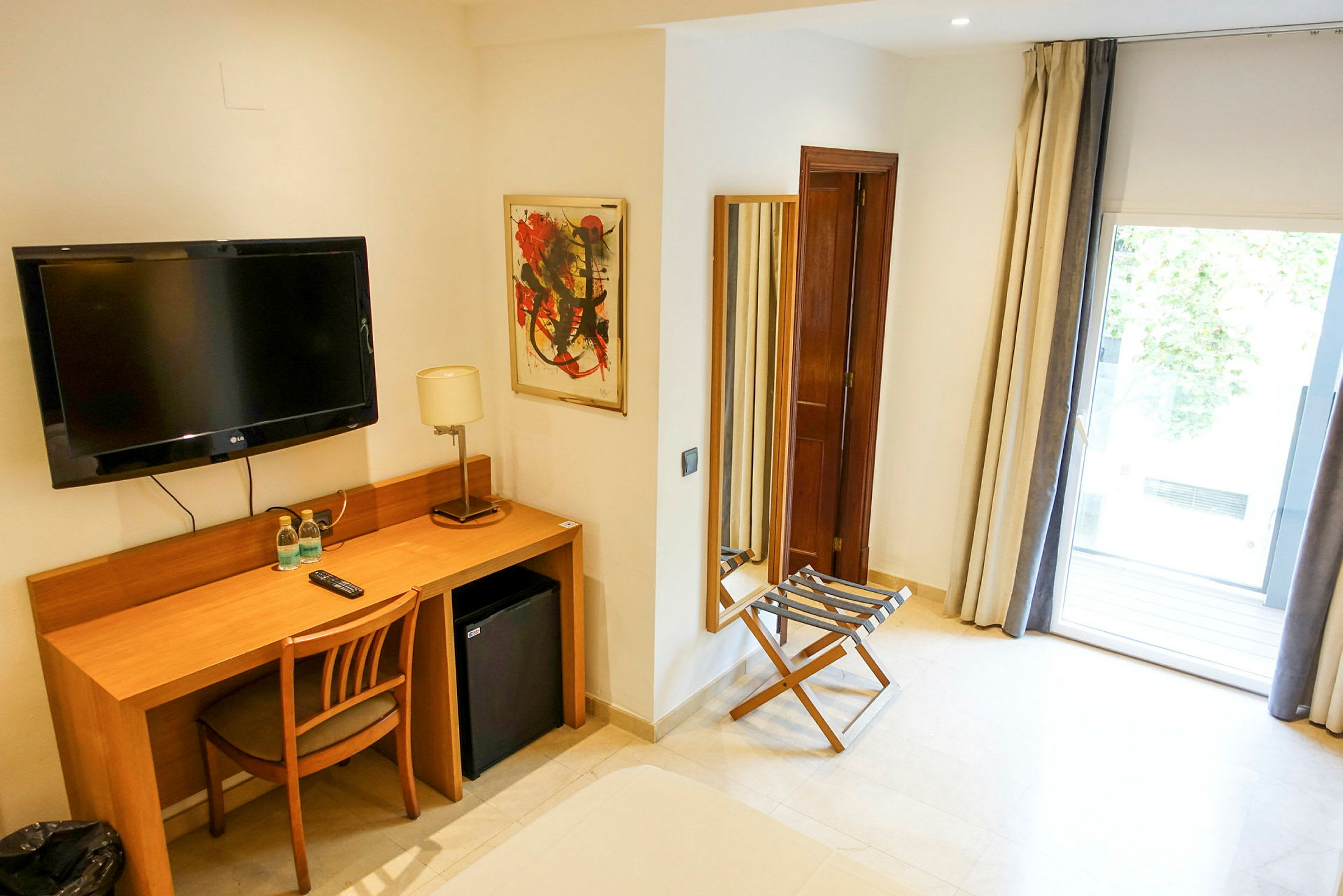 Hotellrum med skrivbord, stol, TV och fönster med utsikt. (AI-genererad text)