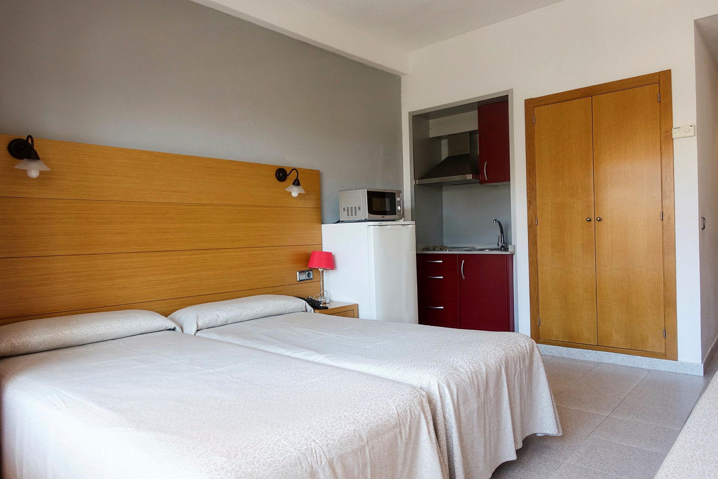 Ett hotellrum med två enkelsängar, en liten kokvrå och en garderob. (AI-genererad text)
