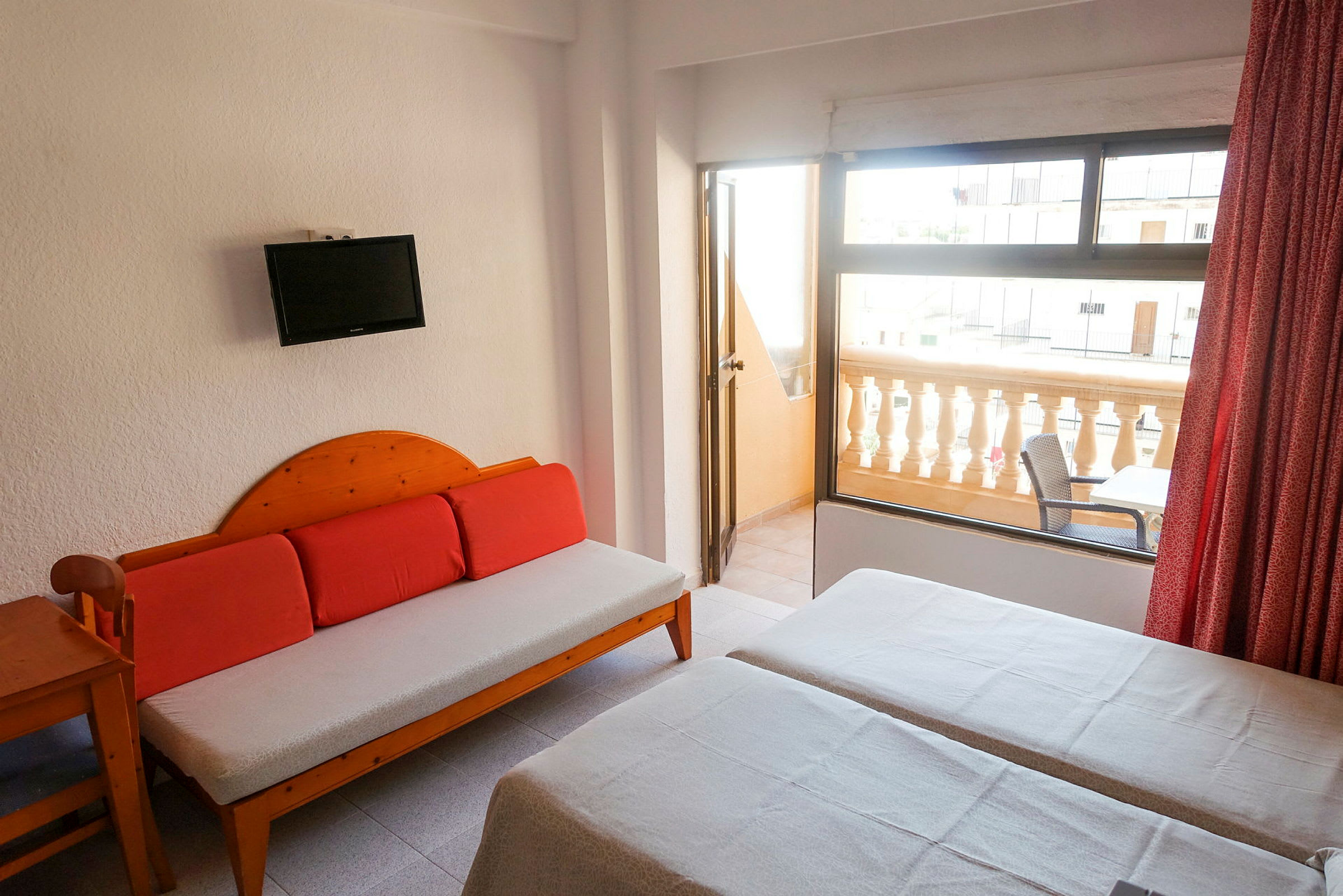 Ett hotellrum med två enkelsängar, en soffa och en balkong utrustad med sittmöbler. (AI-genererad text)