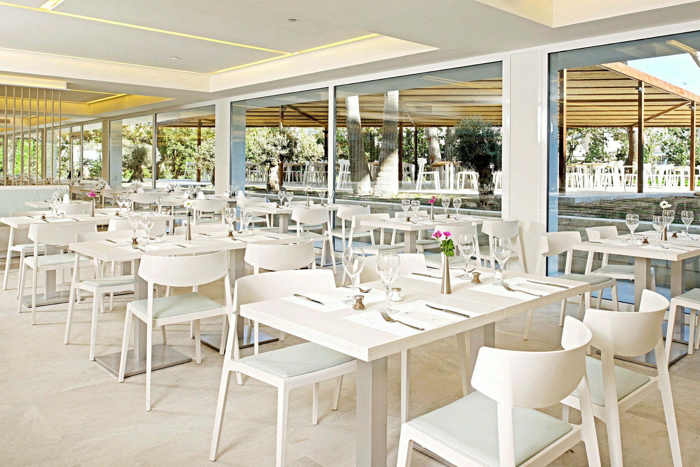 En modern restaurang med vita möbler och bordsuppdukning. (AI-genererad text)
