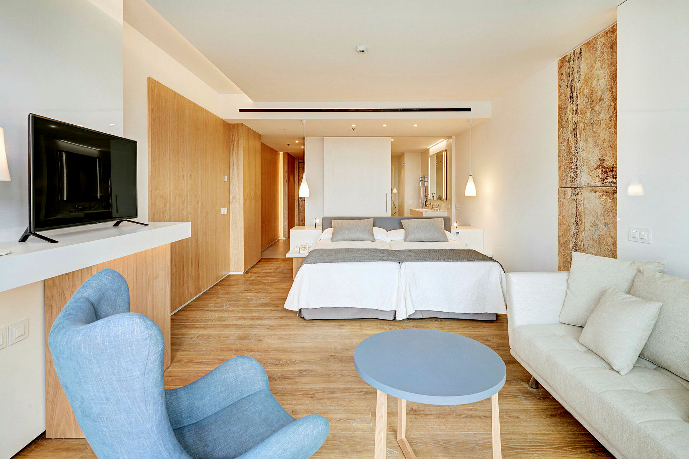 Ett modernt hotellrum med dubbelsäng, sittgrupp och TV. (AI-genererad text)