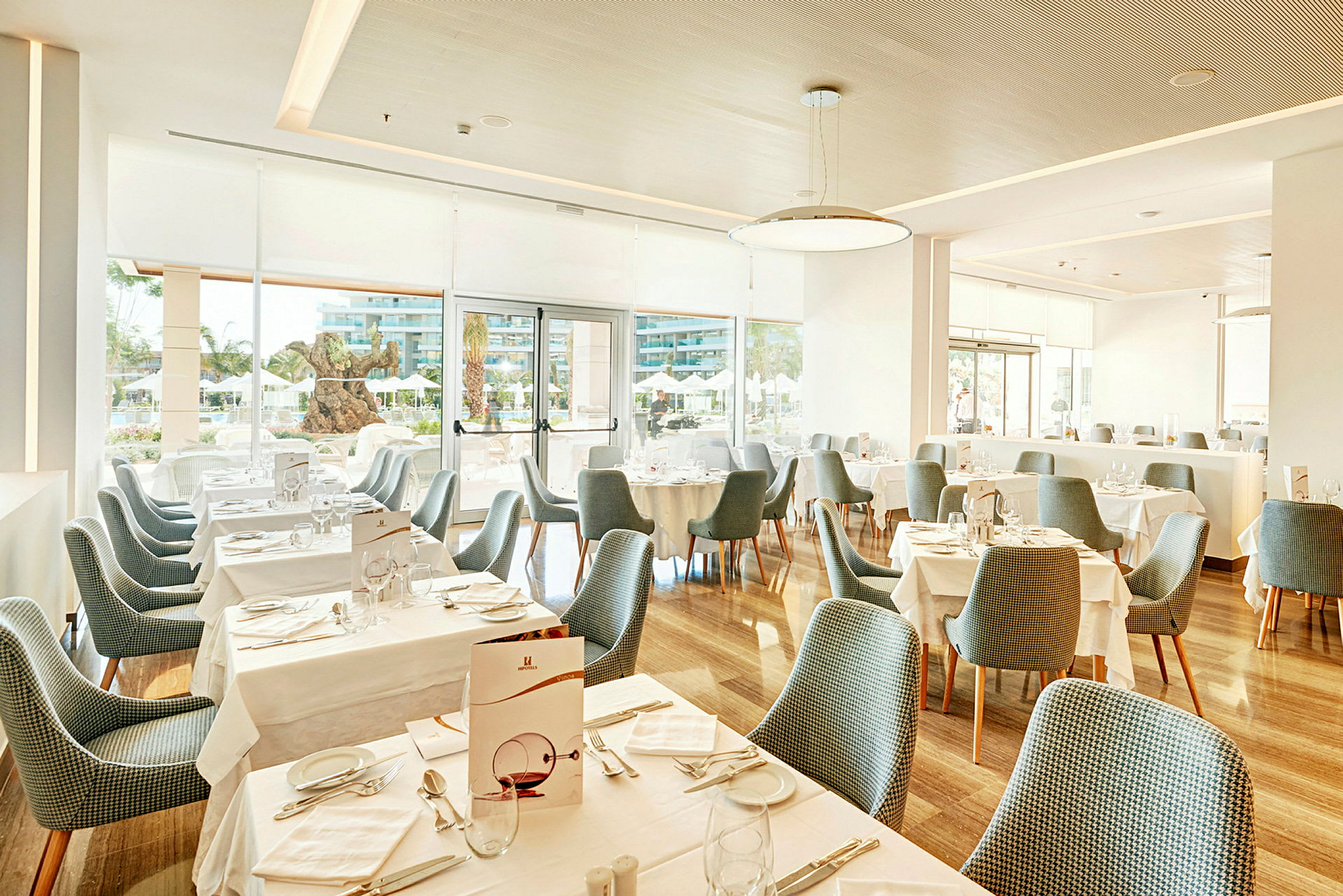 En ljus restaurang med dukade bord och blå stolar. (AI-genererad text)