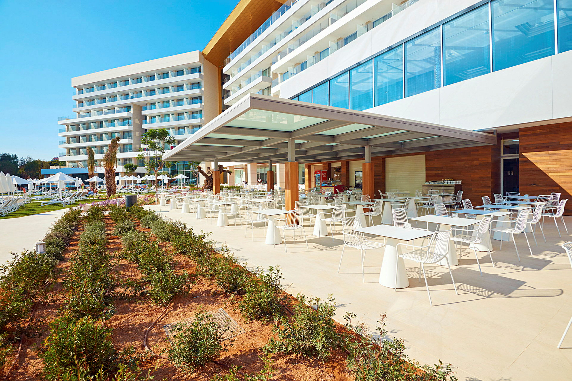 Hotellbyggnad med uteservering och trädgård. (AI-genererad text)