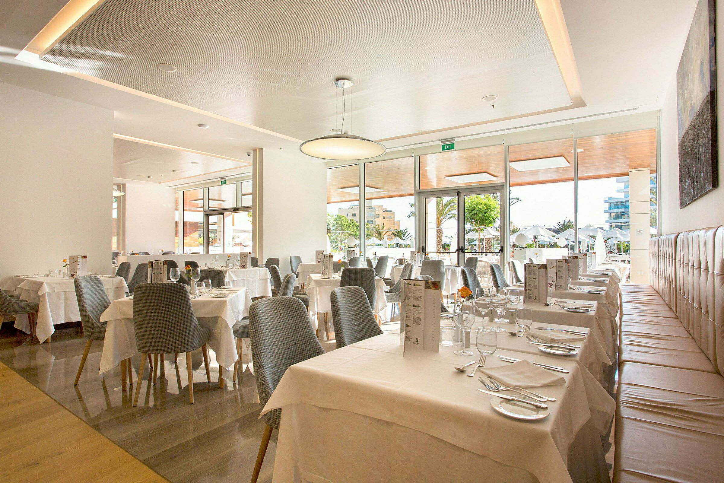 En ljus och modern restaurang med dukade bord och stora fönster. (AI-genererad text)