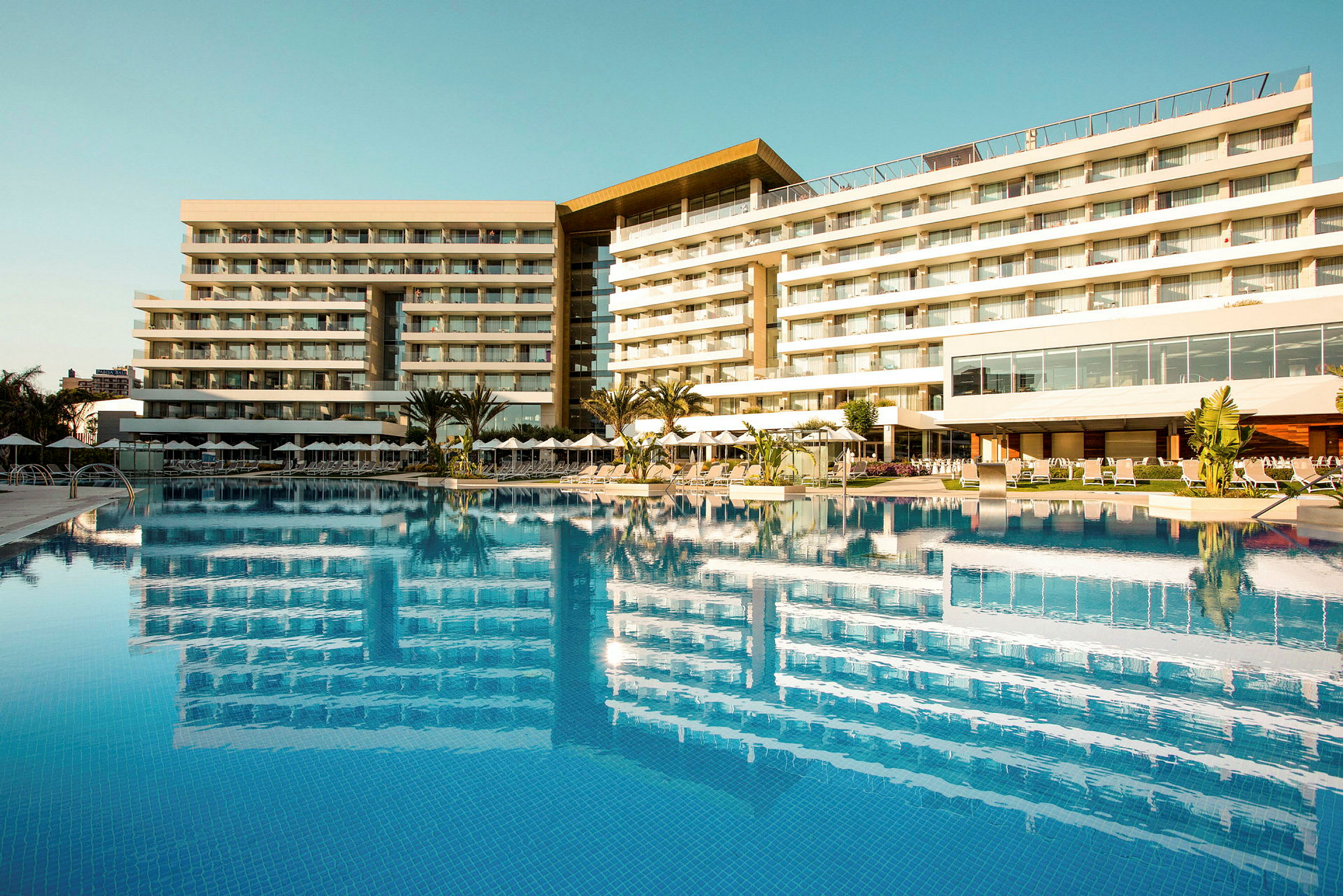 Ett modern hotell med balkonger vid en stor pool. (AI-genererad text)