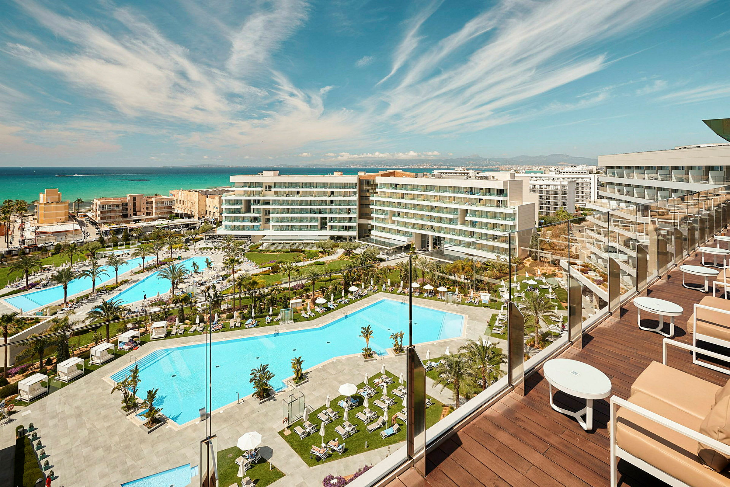 Utsikt över hotellområde med flera pooler och byggnader nära havet. (AI-genererad text)
