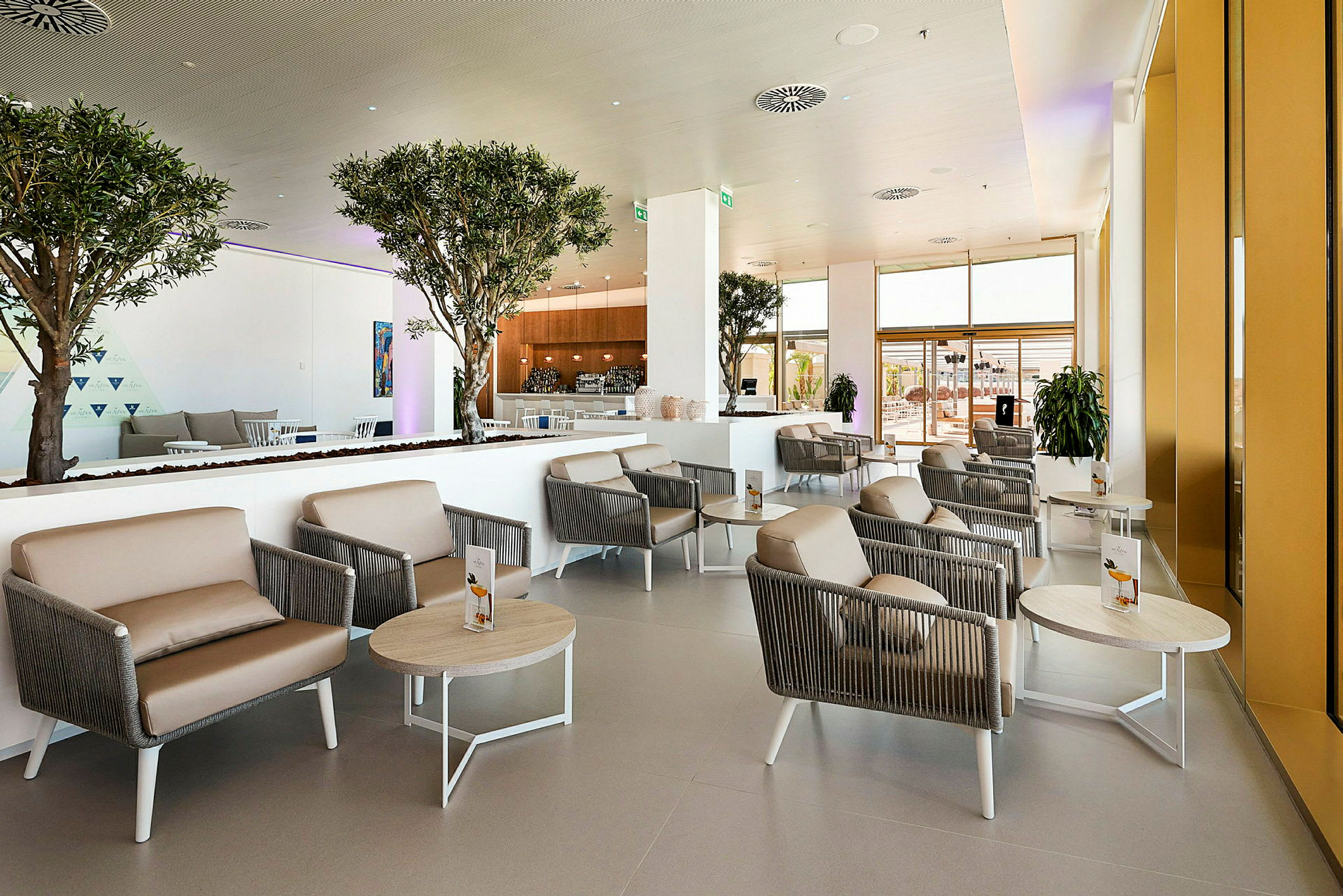 Modernt och ljust hotellobbyområde med sittgrupper och inomhusträd. (AI-genererad text)
