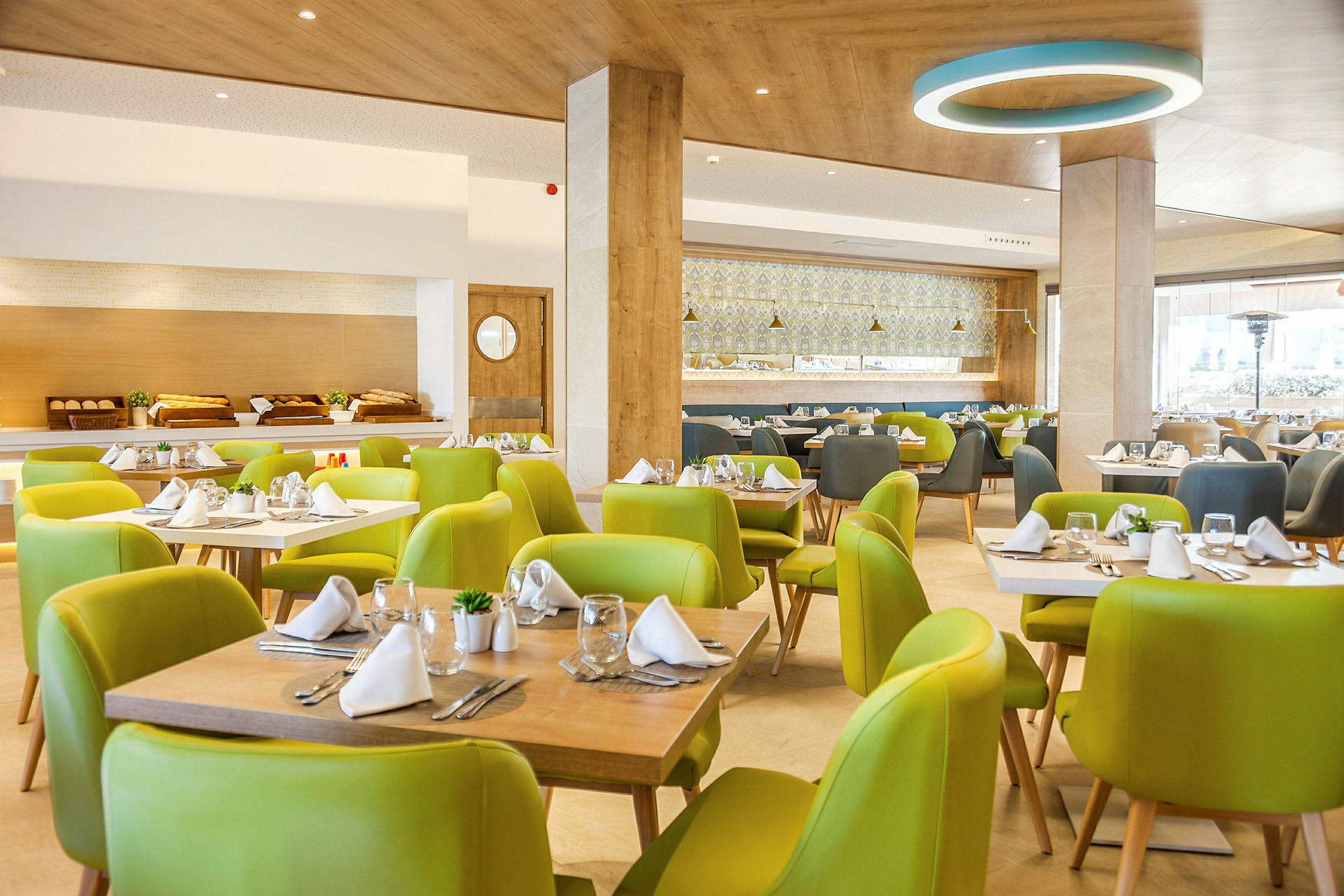 Interiör av en restaurang med gröna stolar och dukade bord. (AI-genererad text)