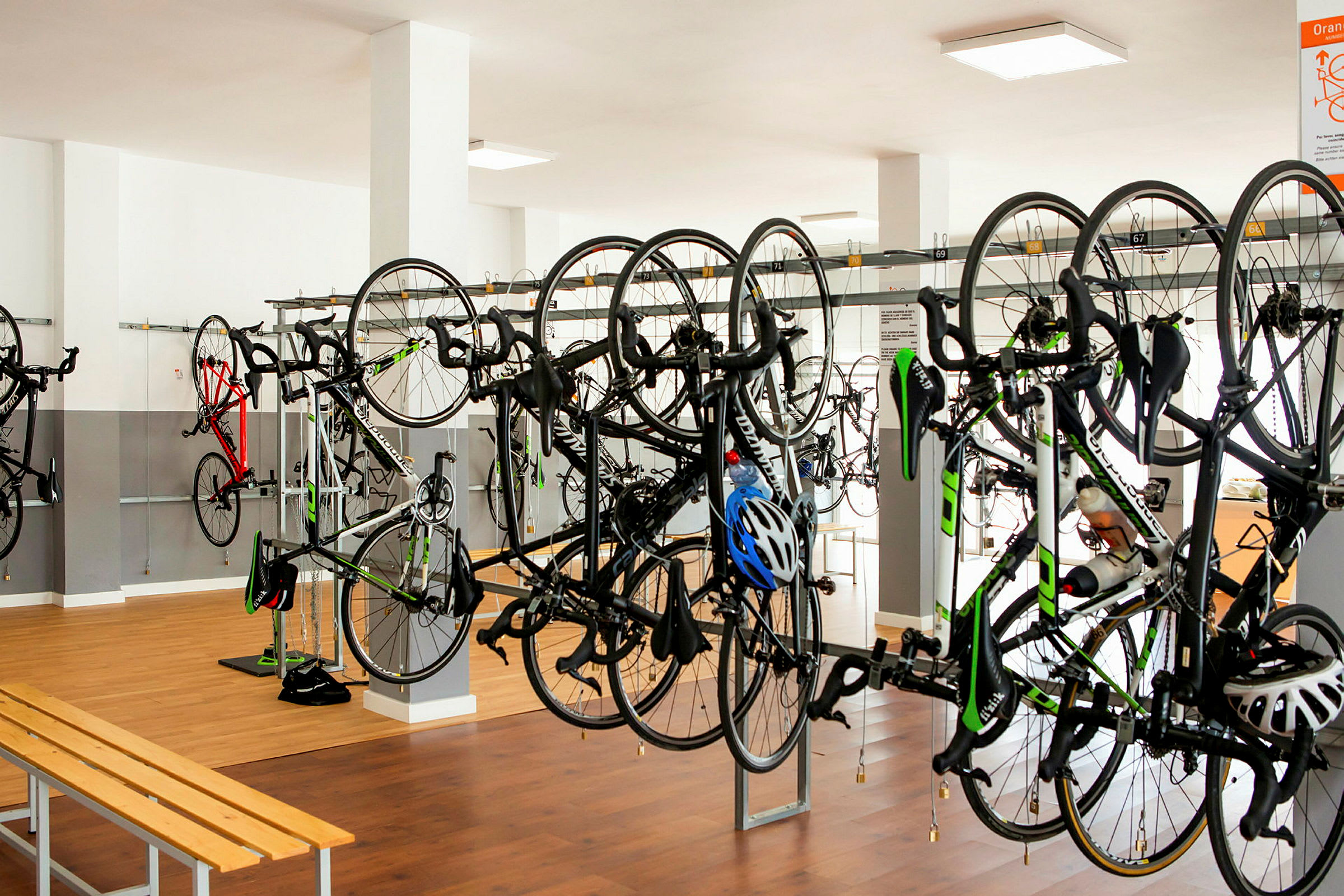Cyklar upphängda på ställ i ett rum med trägolv. (AI-genererad text)