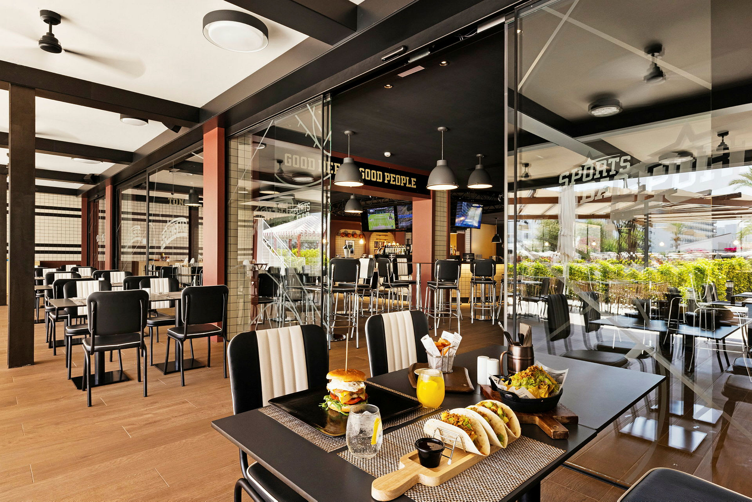En modern restaurang med glasvägg, bordsuppsättningar och synliga maträtter. (AI-genererad text)