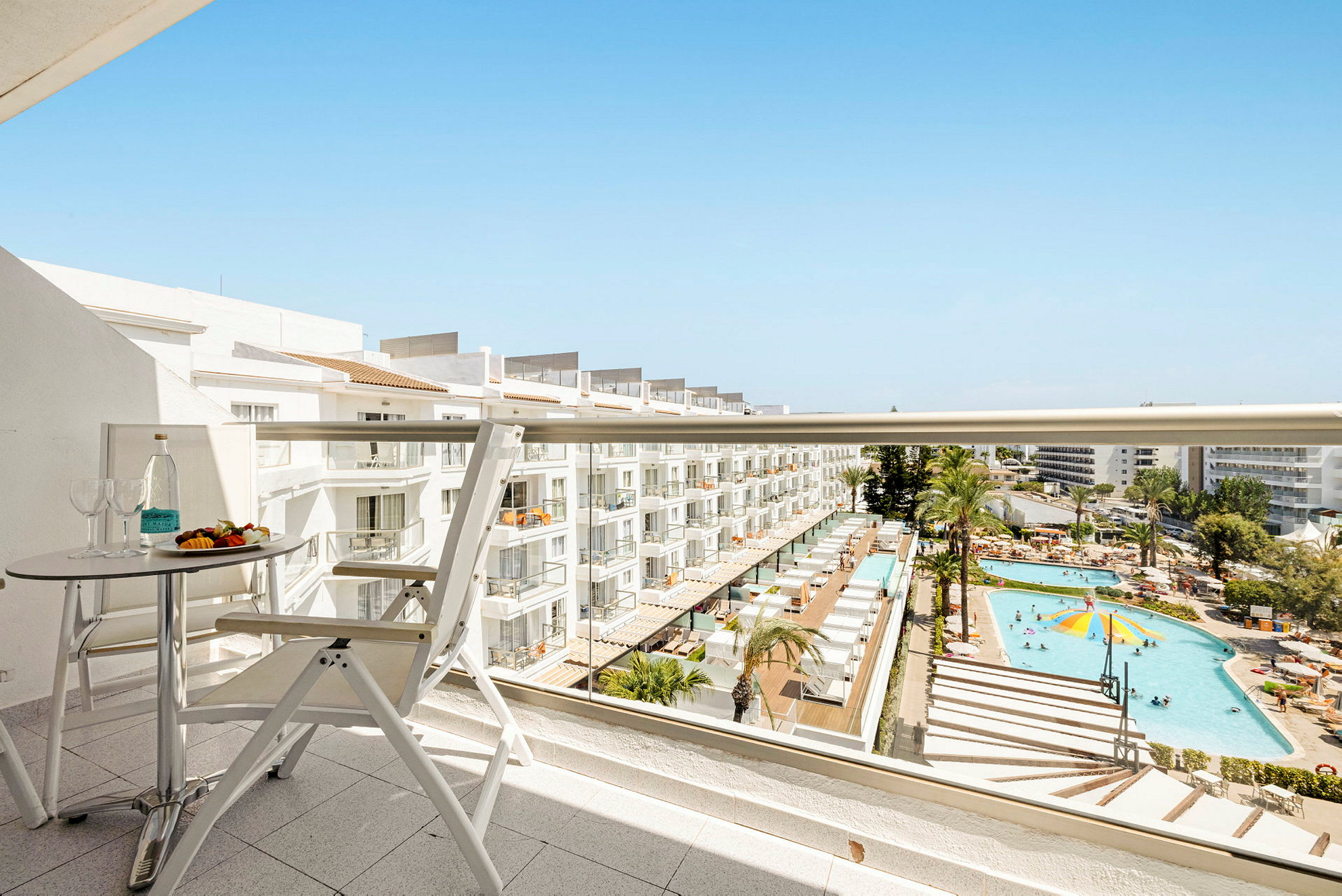 Utsikt från en balkong över hotellområde med pool och solstolar. (AI-genererad text)