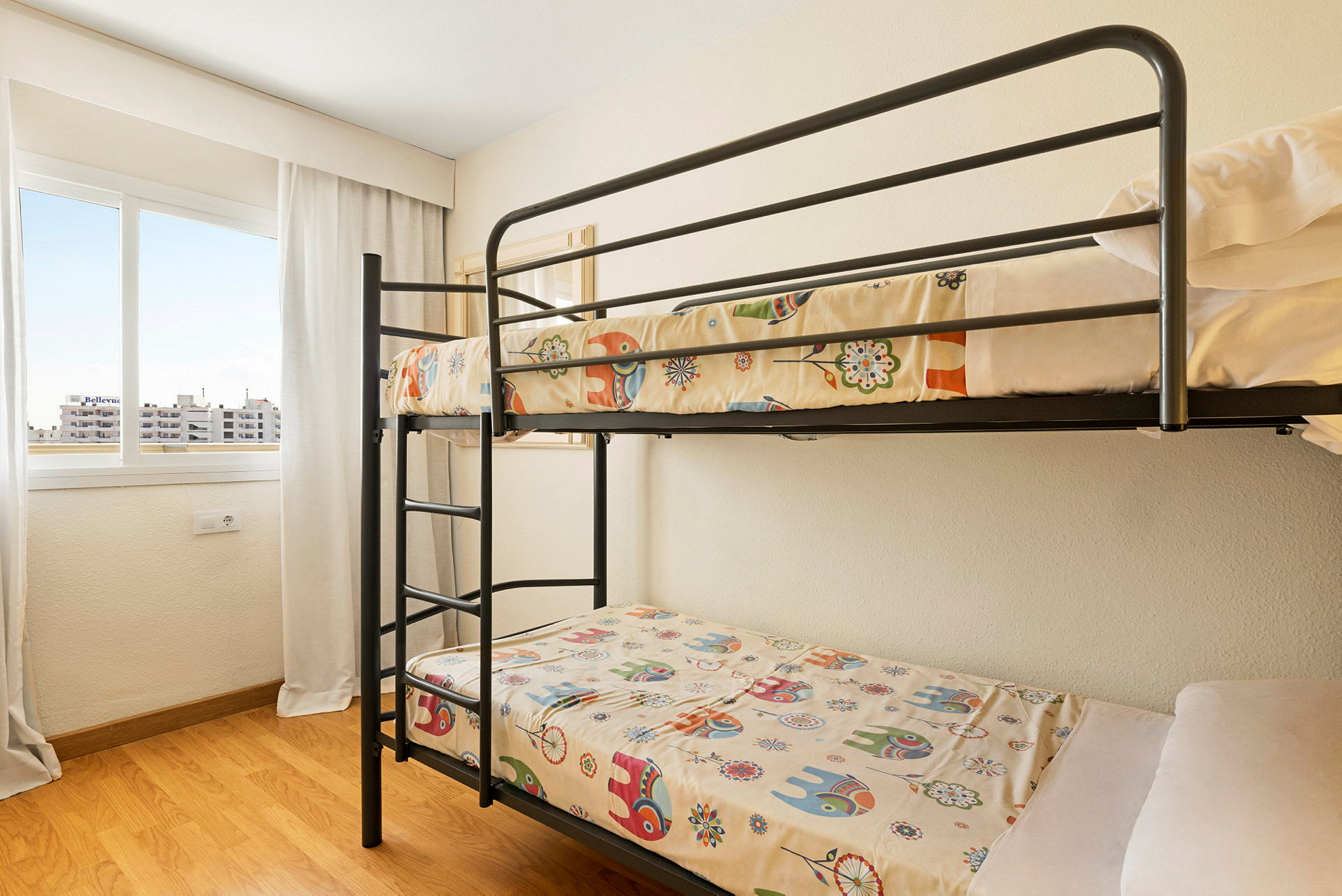 En våningssäng med färgglada sängkläder i ett rum med ljus inredning. (AI-genererad text)