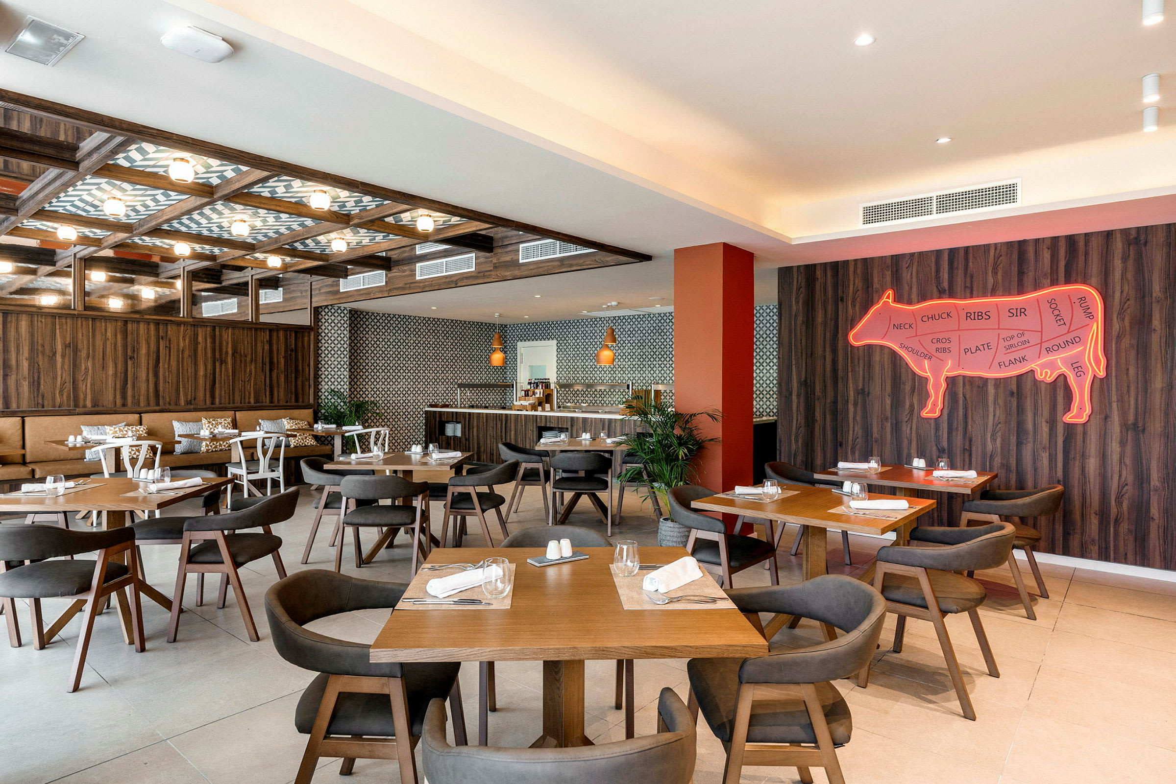 Interiör av en restaurang med flera träbord och stolar, väggdekoration i form av en neonskylt föreställande en ko. (AI-genererad text)