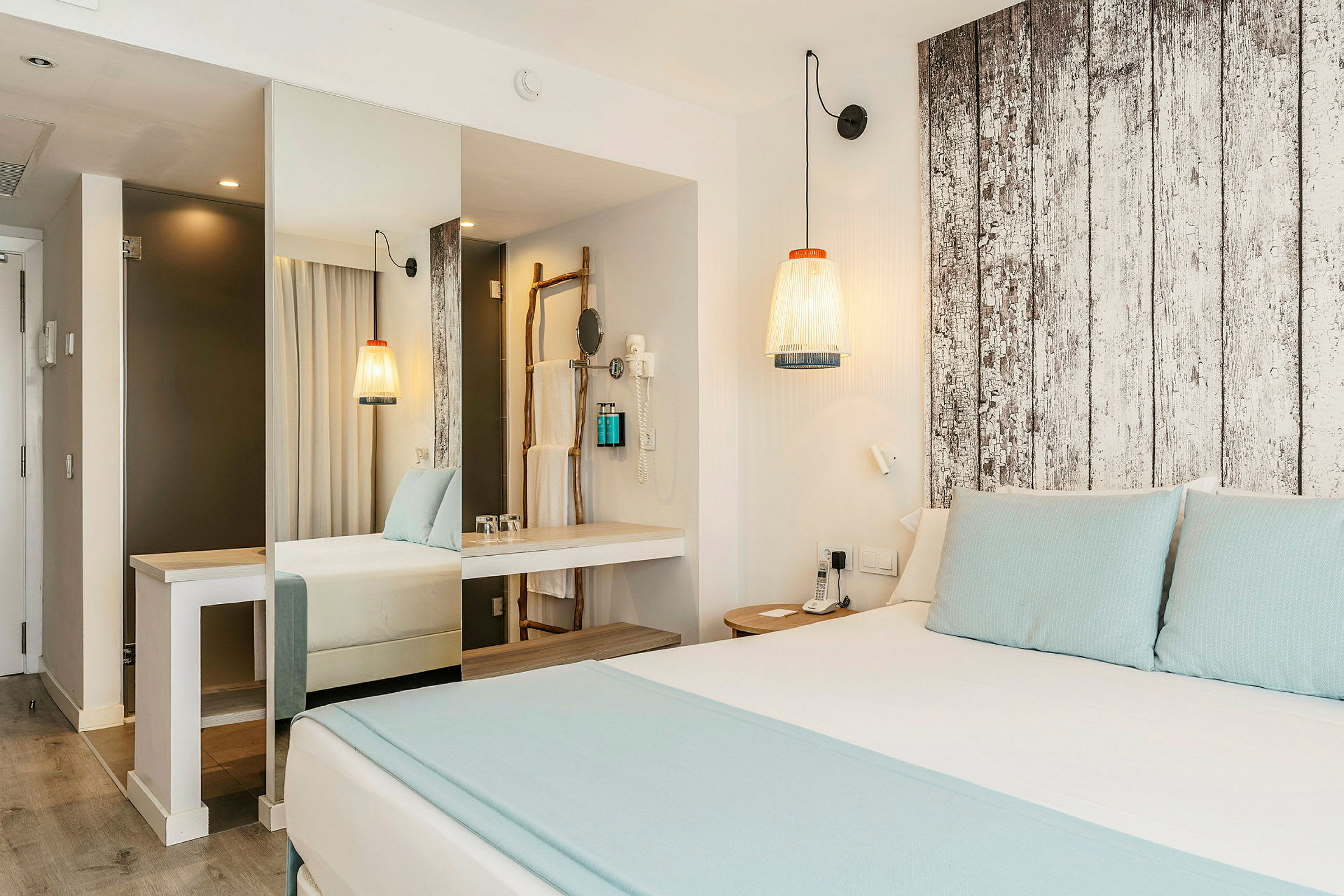 Modernt hotellrum med dubbelsäng, ljus inredning och trädetaljer. (AI-genererad text)