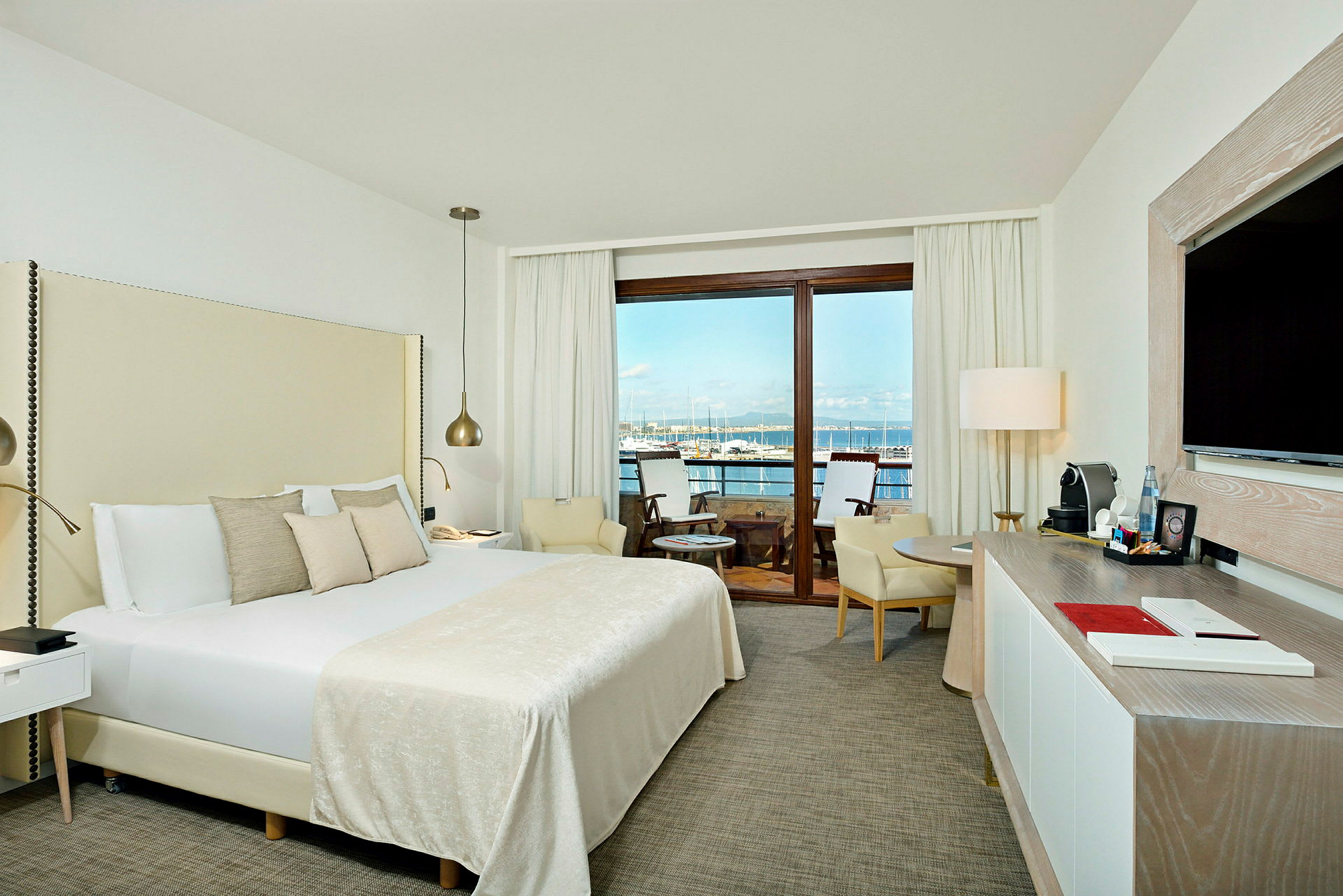 Ett hotellrum med en stor säng och en balkong med utsikt över en marina. (AI-genererad text)