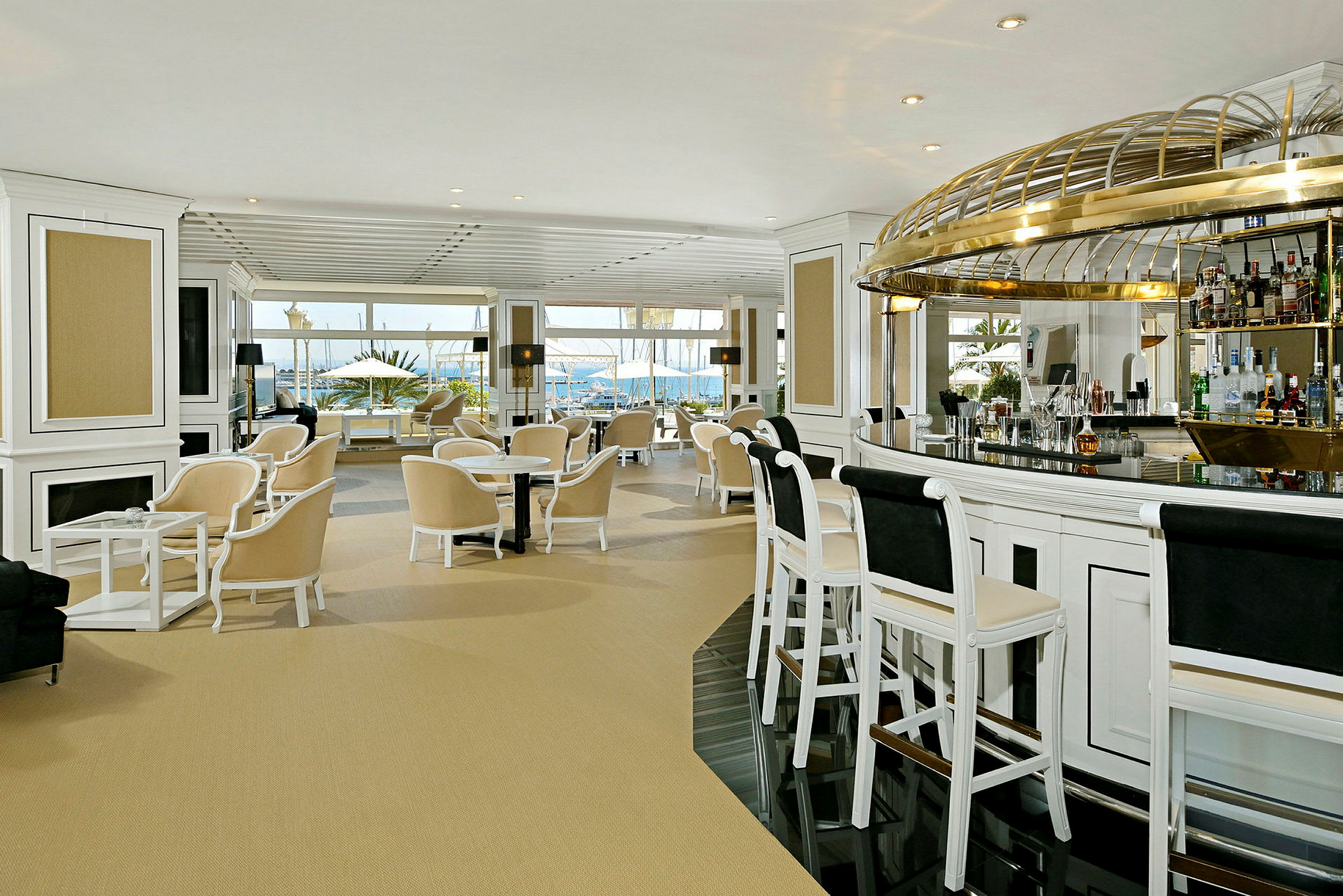 Interiör av en elegant hotellbar med ljusa möbler och stora fönster som vetter mot havet. (AI-genererad text)