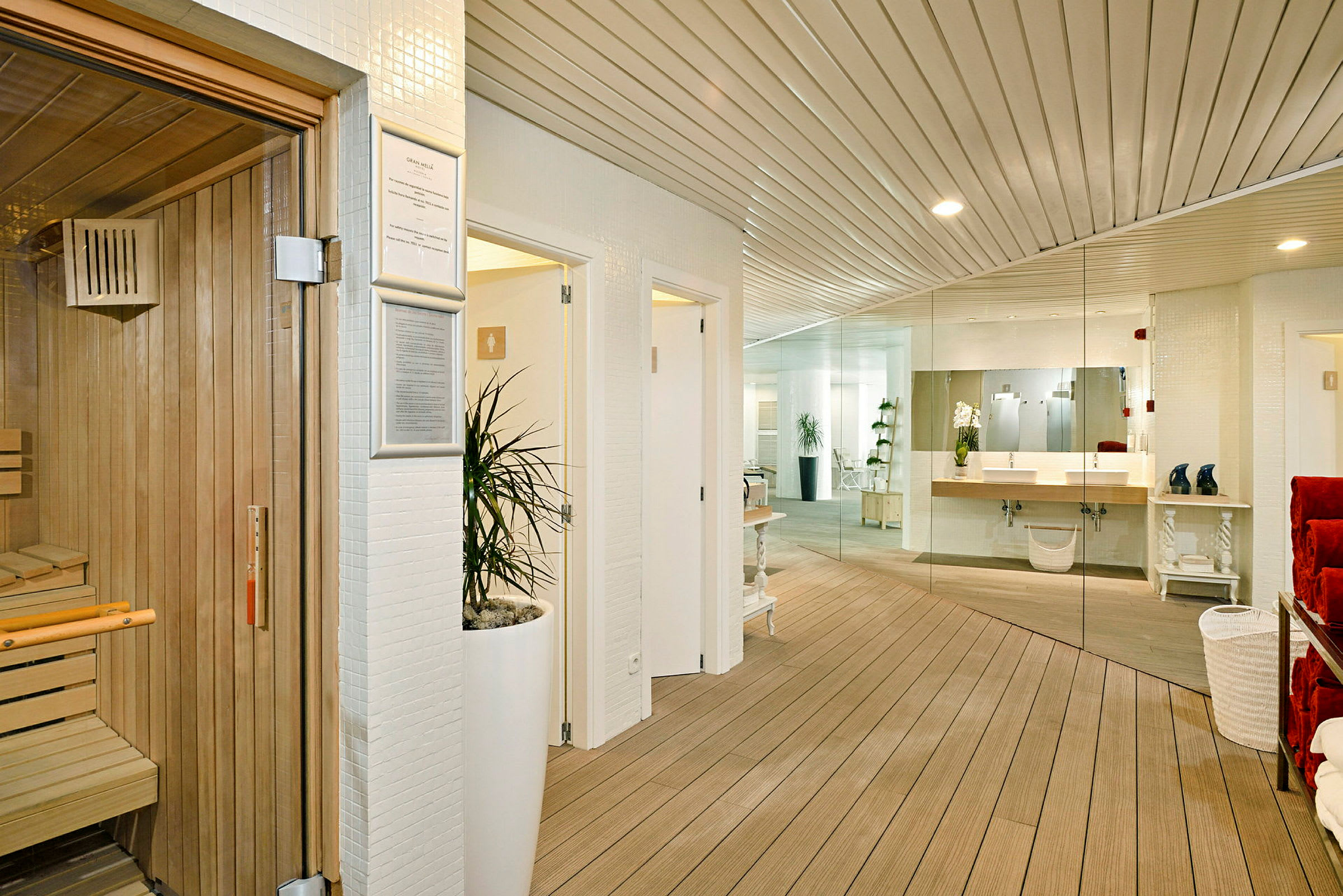 Interiör av ett spa, med en bastu till vänster, en pentryyta och spegelvägg i bakgrunden. (AI-genererad text)