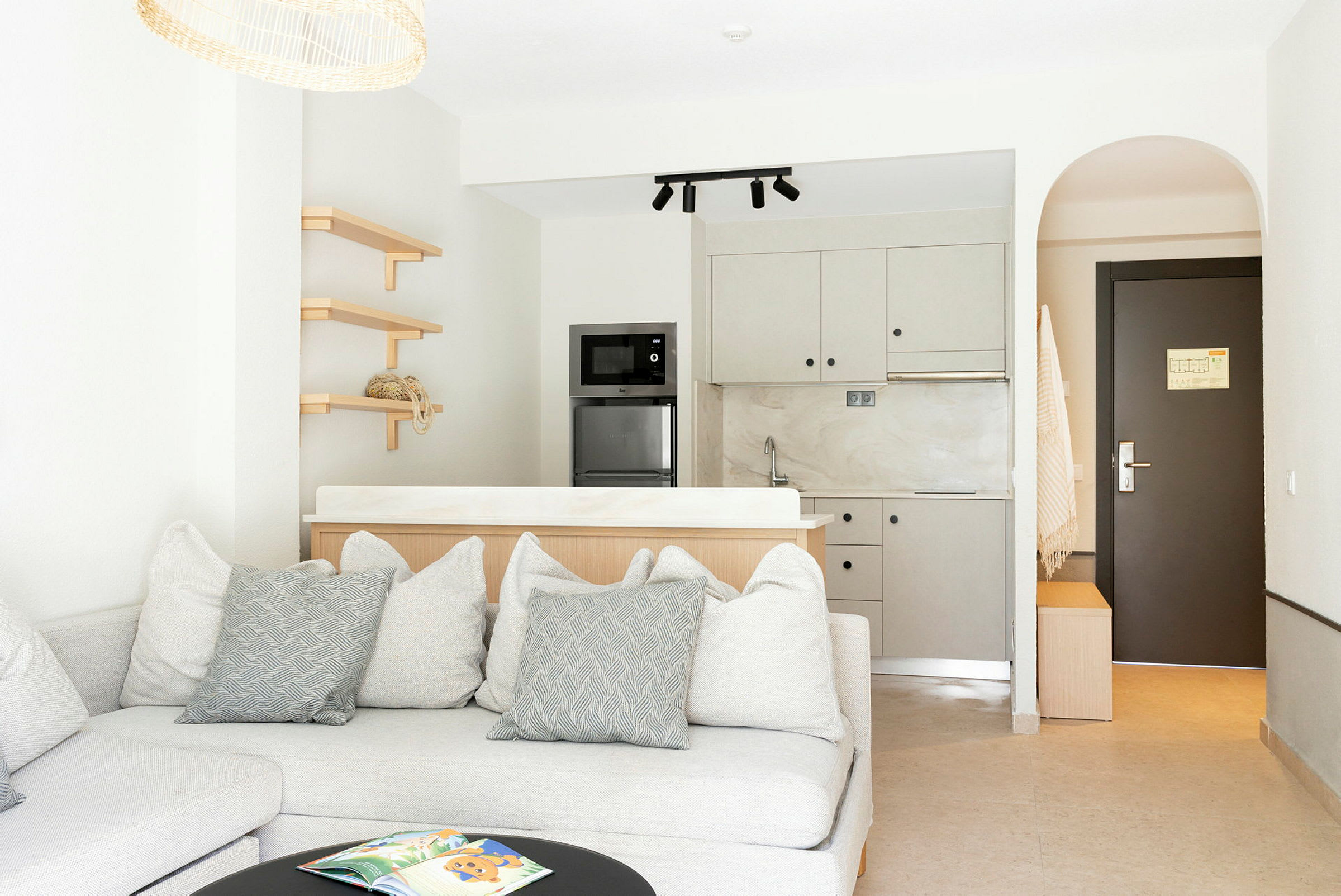 Modern hotellrum med soffa, kök och dörr. (AI-genererad text)