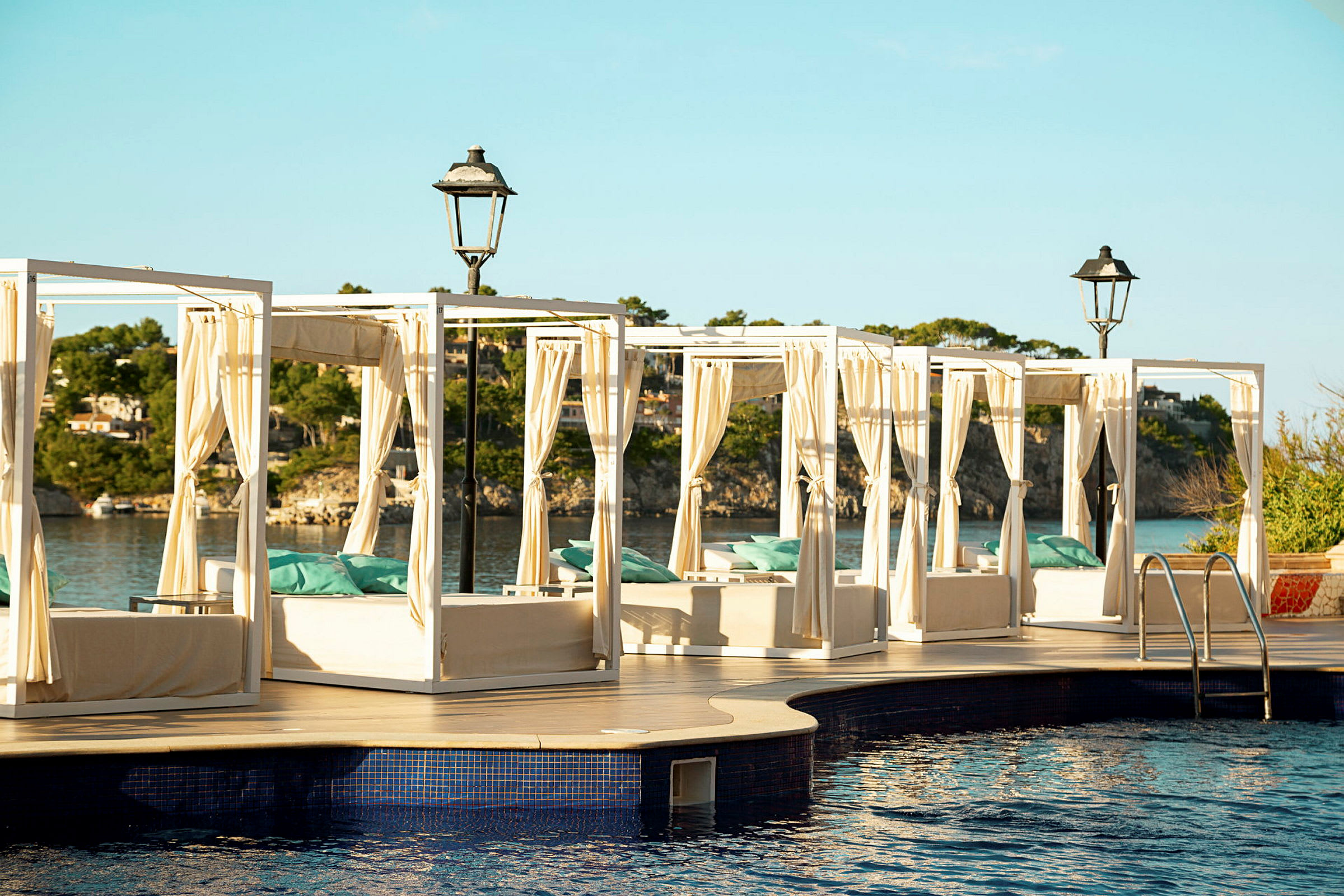Solbäddar med gardiner vid en pool med utsikt över havet. (AI-genererad text)