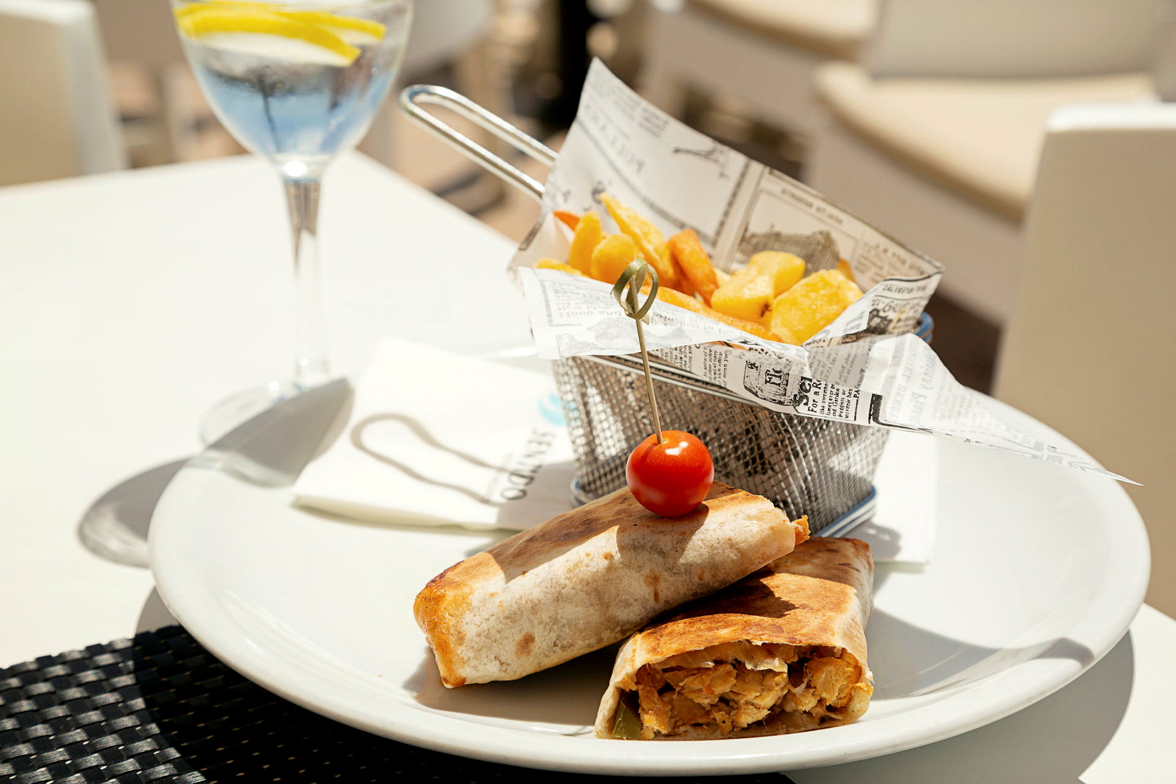 En måltid med wraps, pommes frites och en glasdryck. (AI-genererad text)