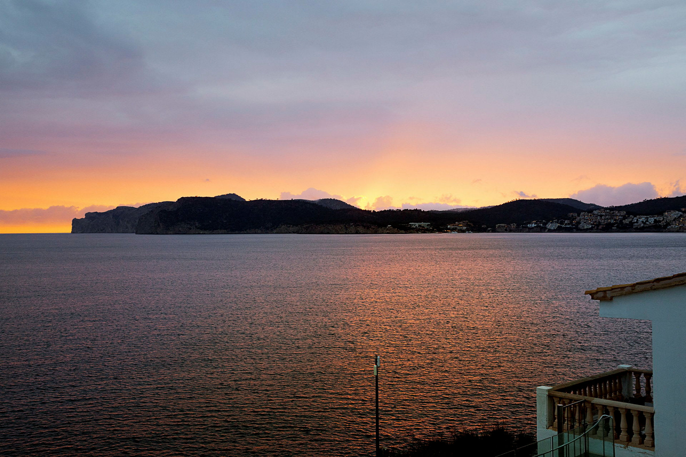 Solnedgång över en bergig kustlinje vid havet. (AI-genererad text)