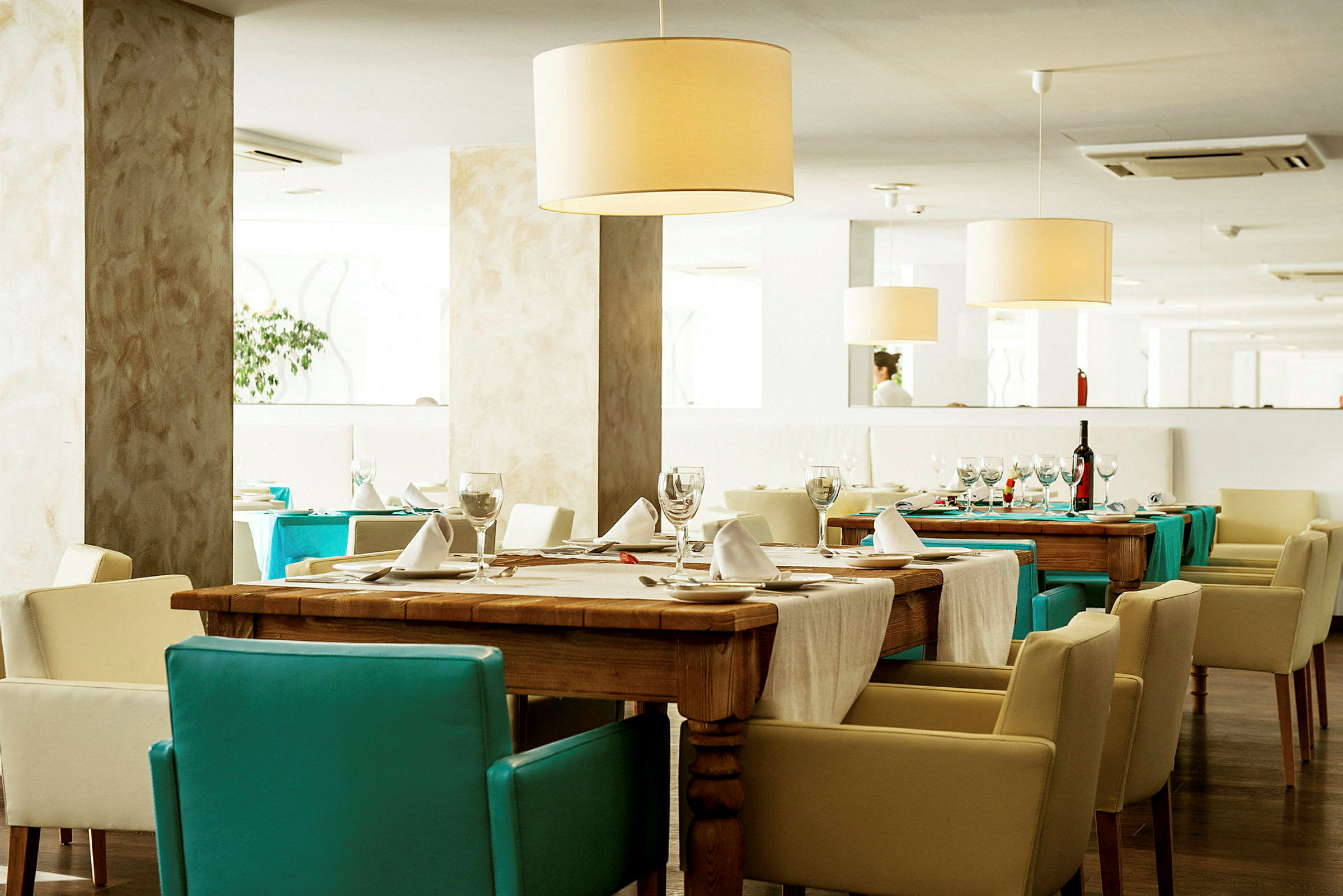 Ett elegant restauranginteriör med dukade bord och ljusa stolar. (AI-genererad text)