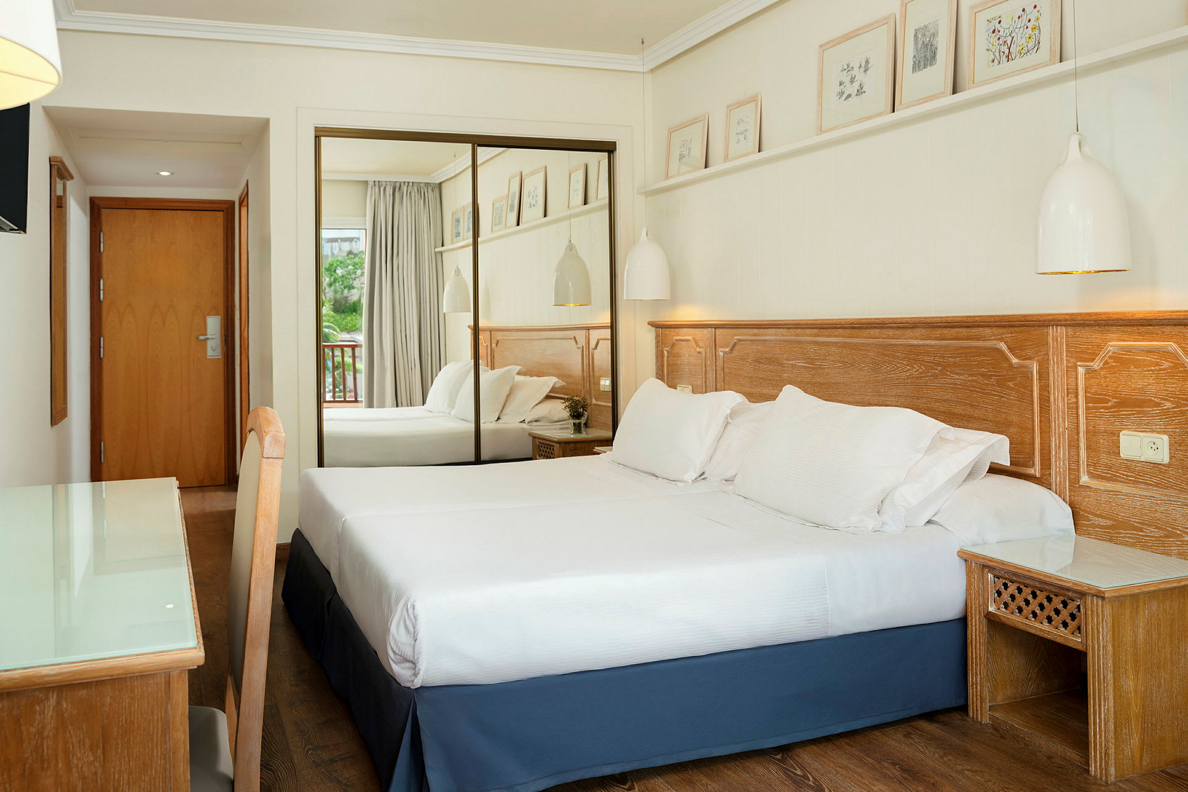 Ett hotellrum med en dubbelsäng, trädetaljer och spegeldörrar. (AI-genererad text)