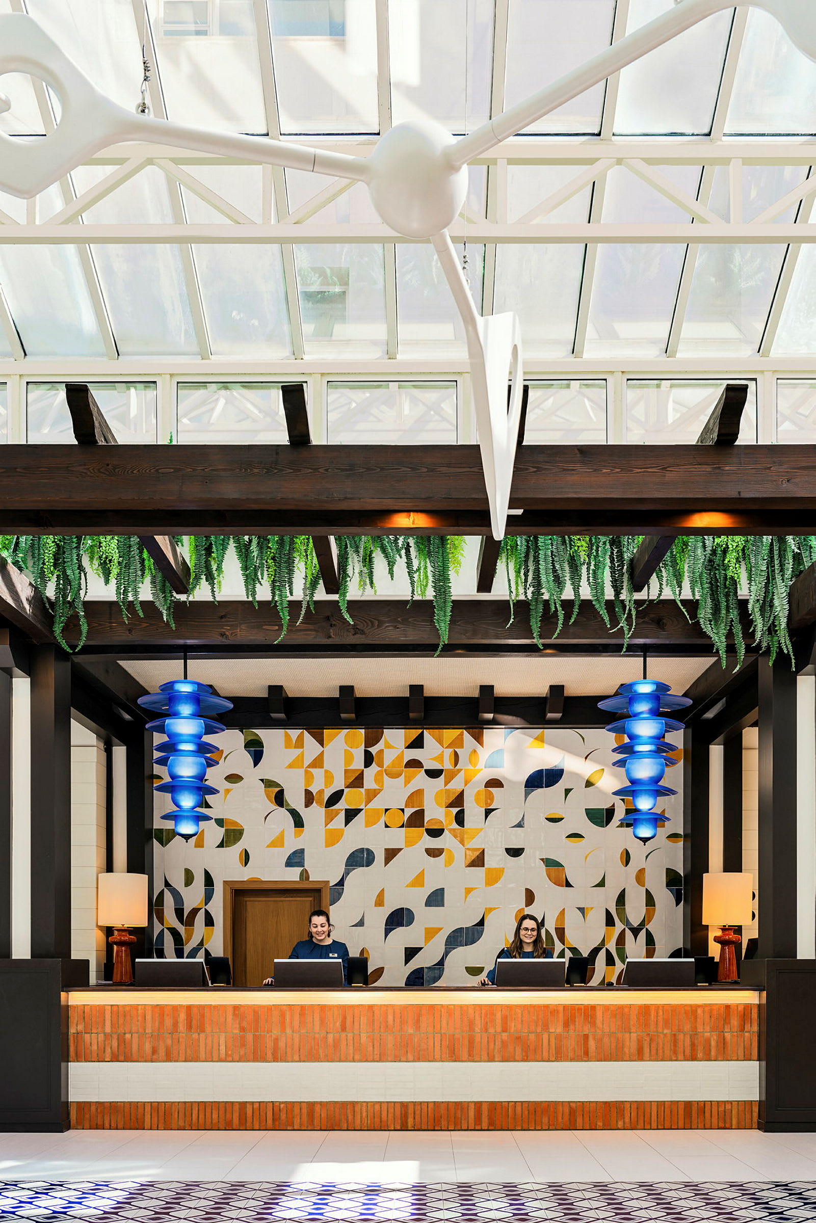 Receptionen i ett hotell med utsmyckad vägg och tak med gröna växter. (AI-genererad text)