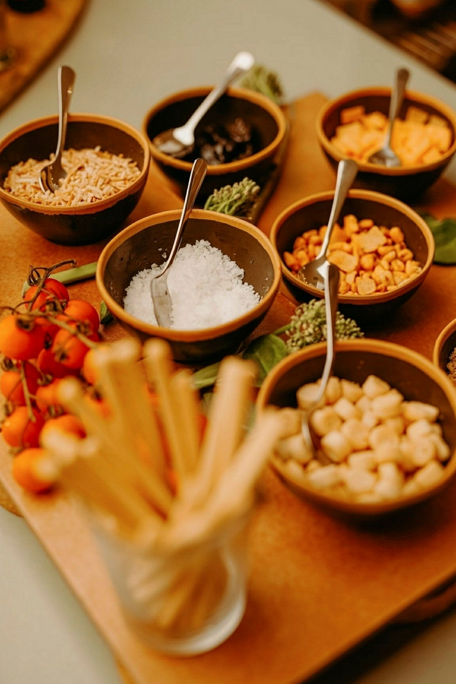En samling små skålar med olika ingredienser, inklusive tomater och brödpinnar. (AI-genererad text)