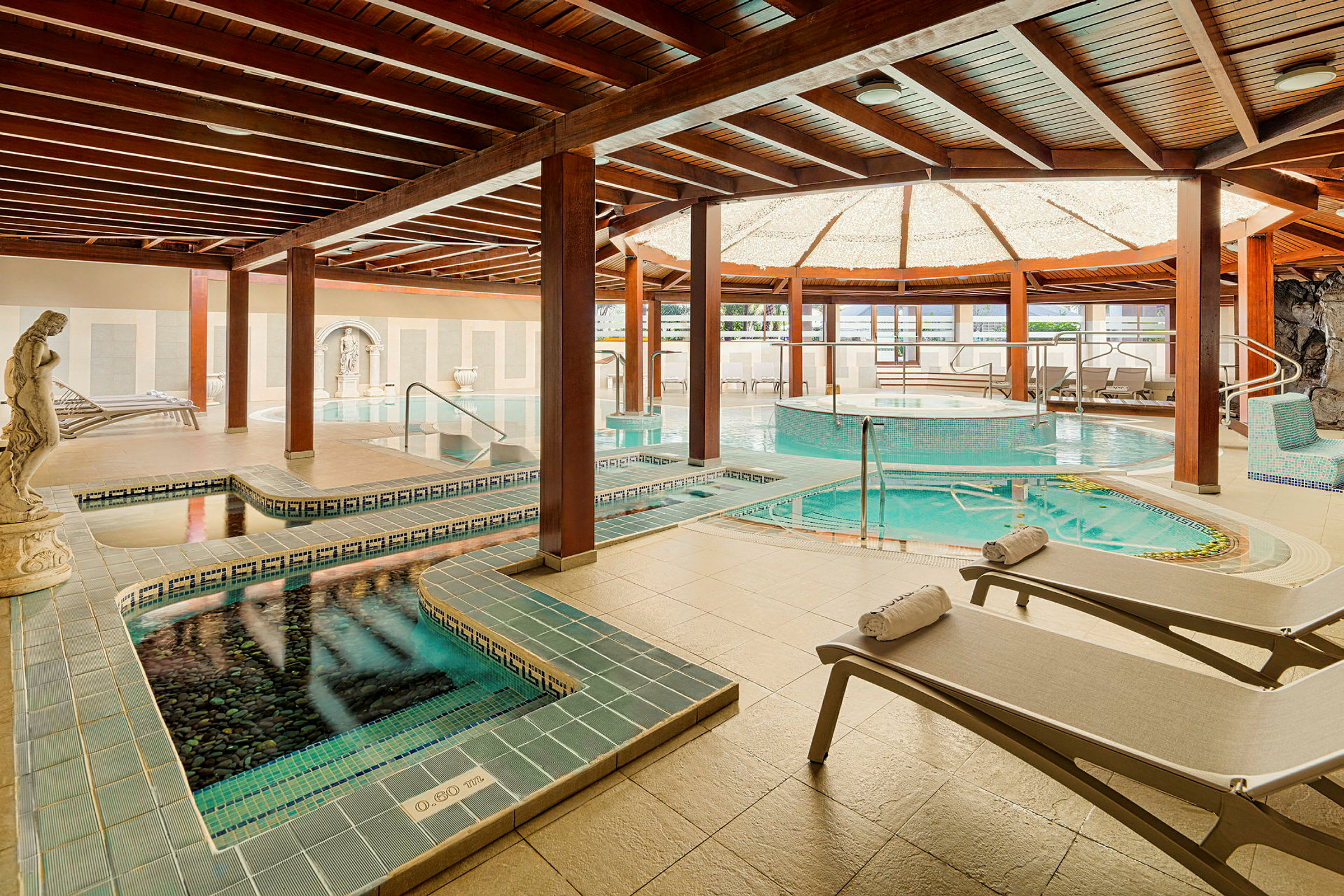 Interiör av ett spa med flera pooler, vilstolar och elegant inredning. (AI-genererad text)