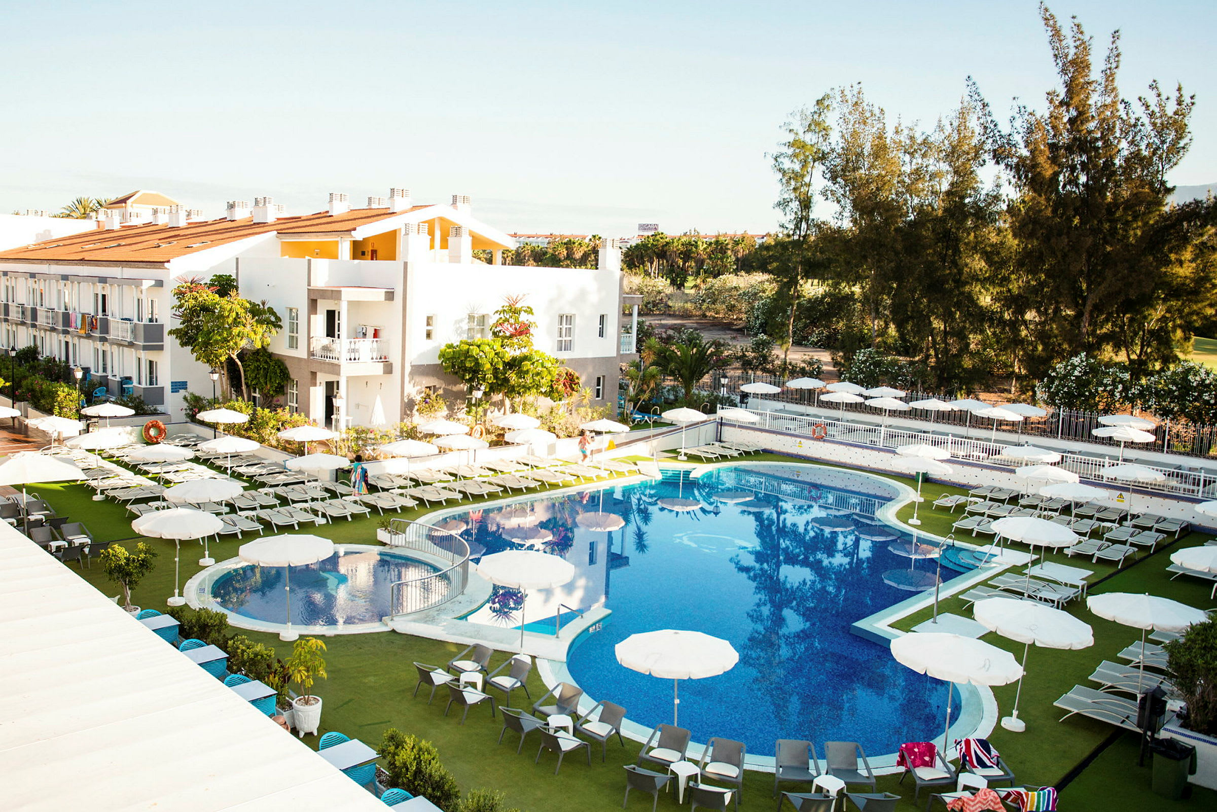 Hotellområde med pool, solstolar och parasoller. (AI-genererad text)