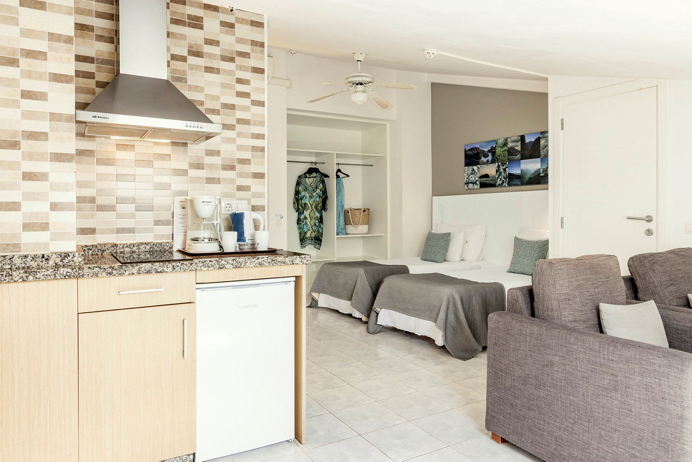 Ett öppet hotellrum med ett pentry, sängar och sittmöbler. (AI-genererad text)