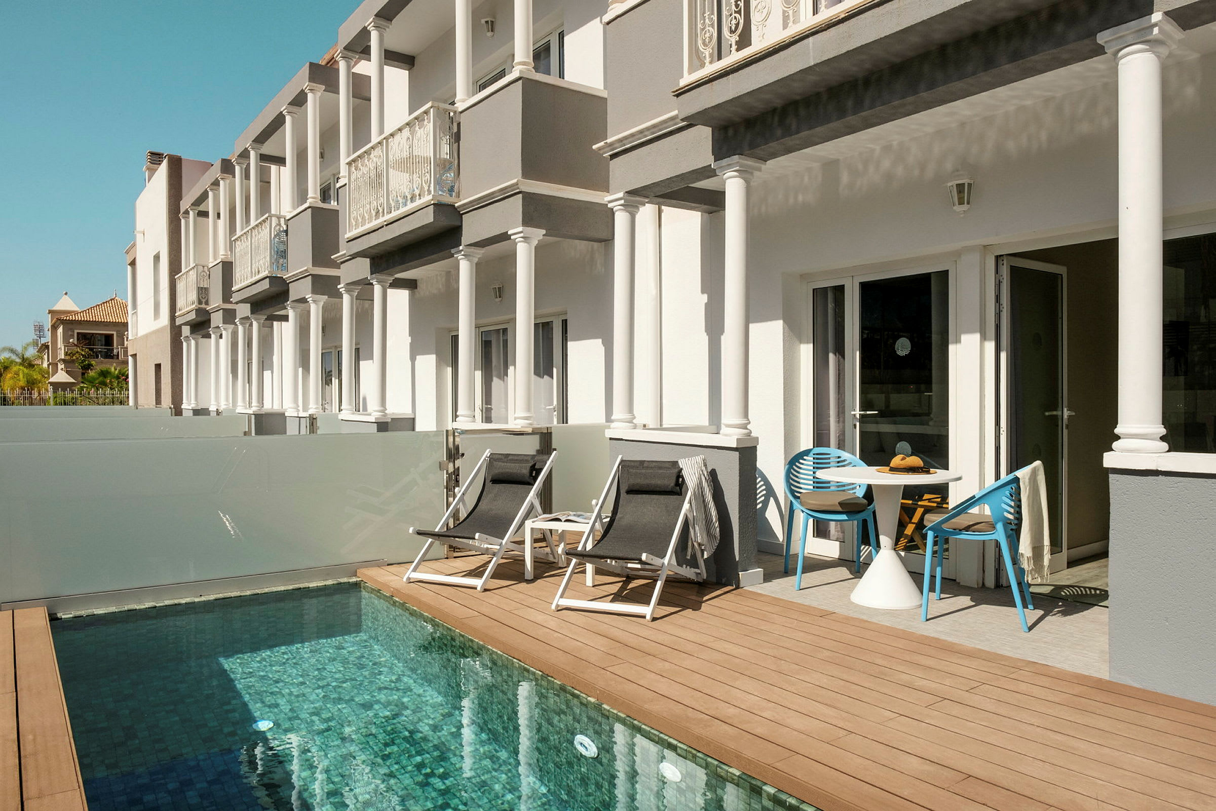 Byggnader med terrass intill en liten pool. (AI-genererad text)