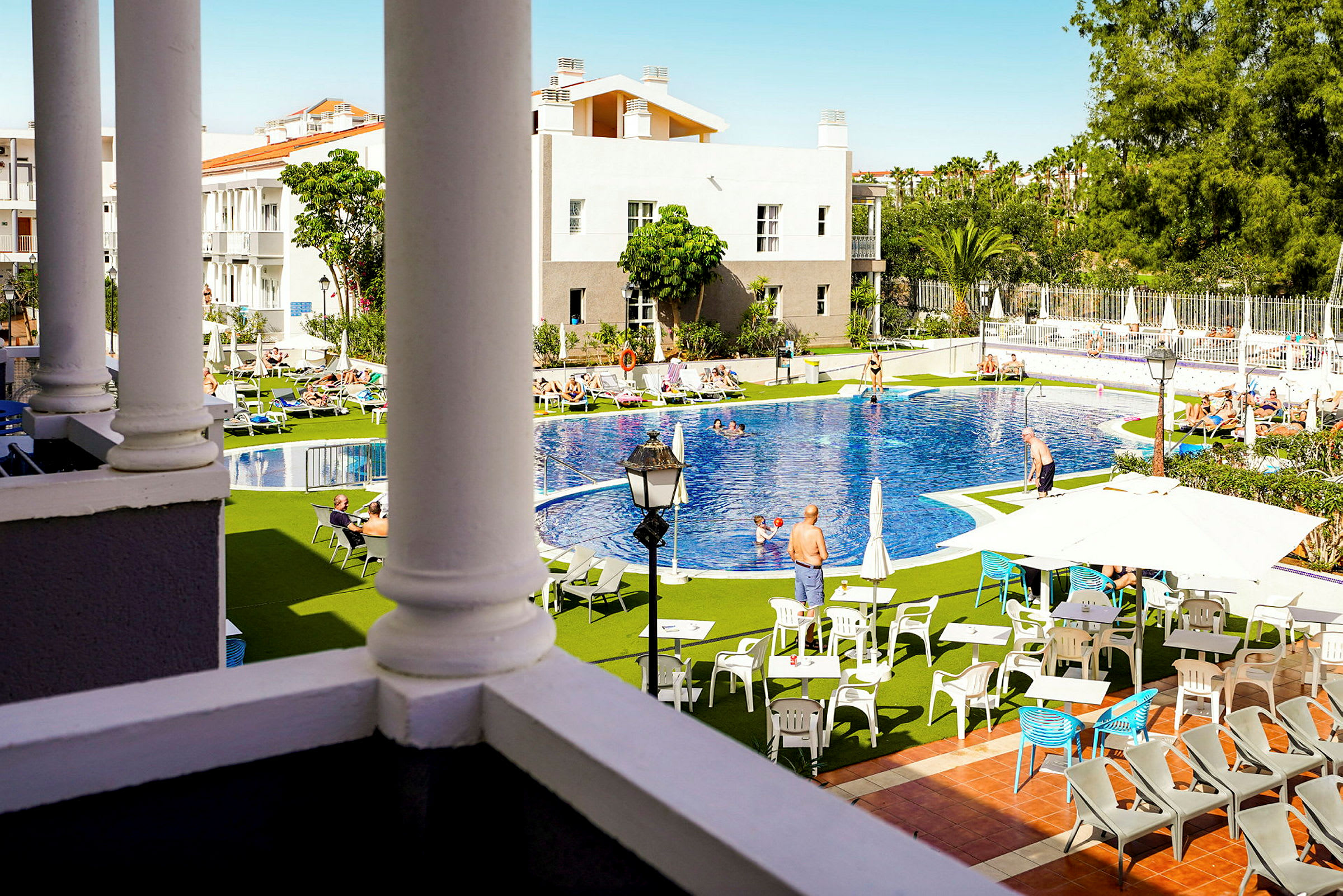 Utsikt över en hotellets poolområde med solstolar, parasoller och bord. (AI-genererad text)