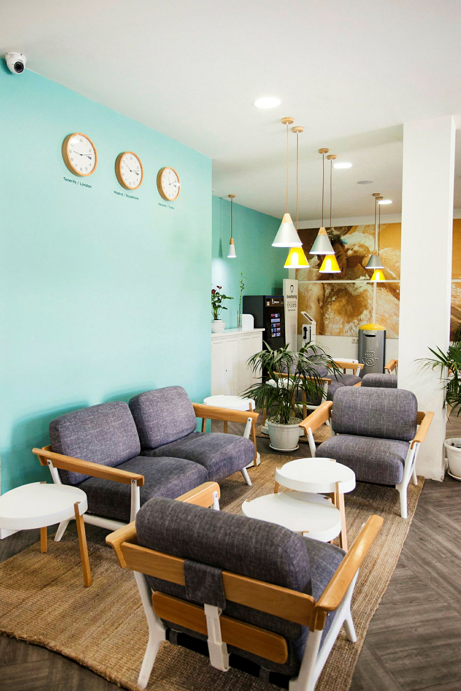 Lounge med blå fåtöljer, vita bord och väggklockor. (AI-genererad text)