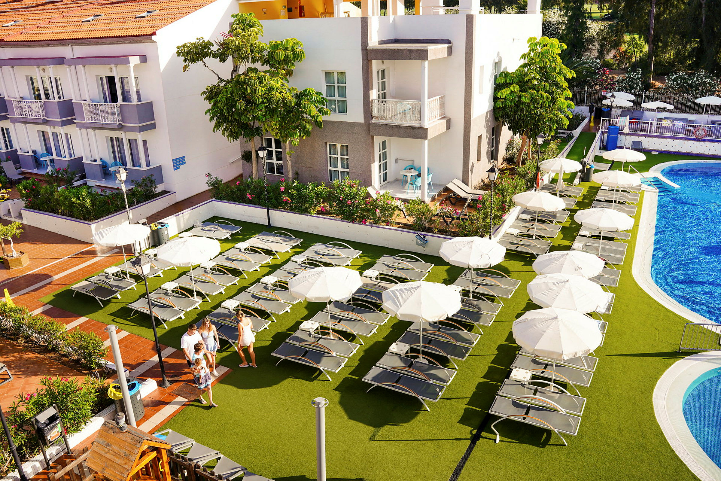 En bild av ett hotellområde med solstolar, parasoller och en pool. (AI-genererad text)