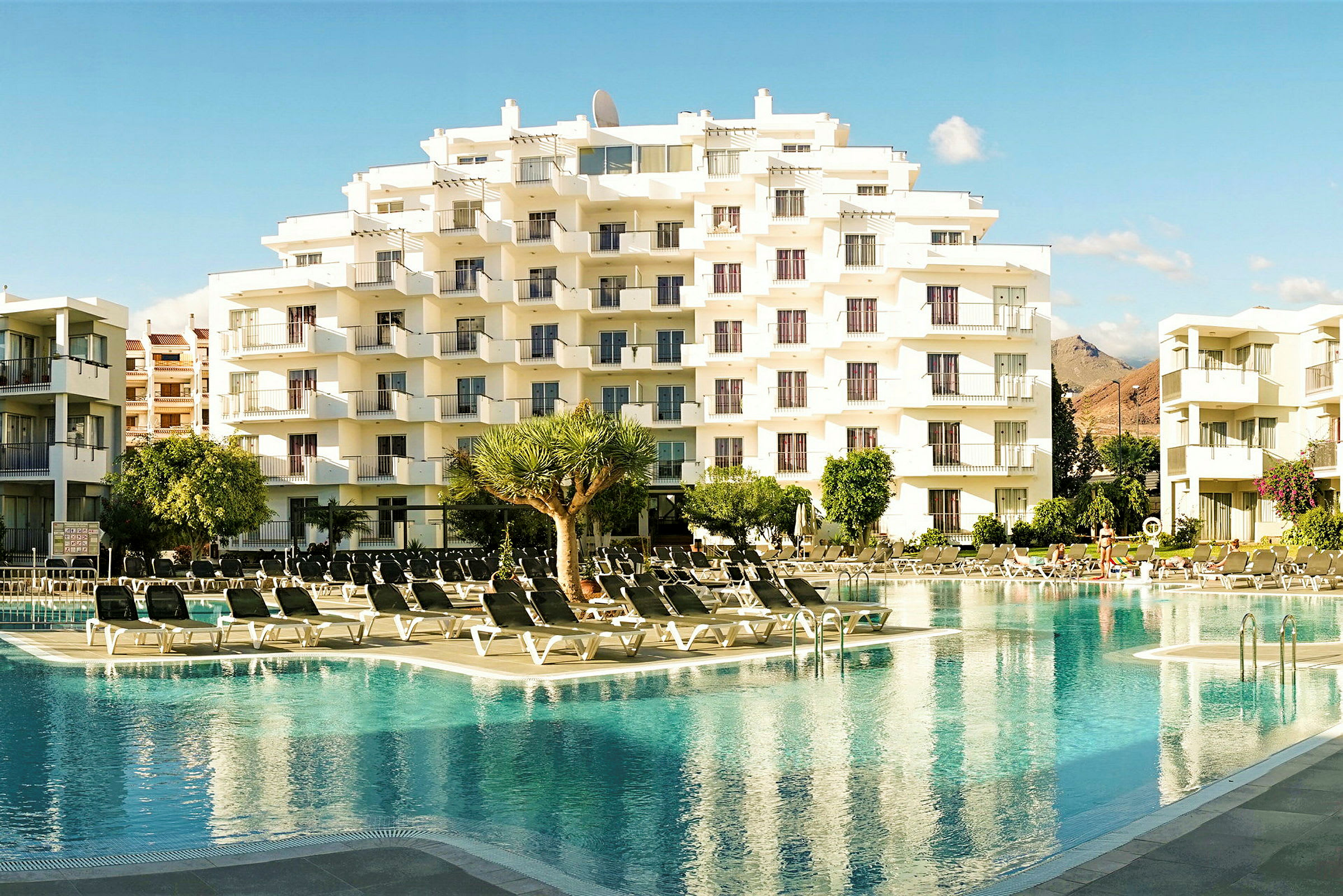 Ett hotell med flera våningar bredvid en pool. (AI-genererad text)
