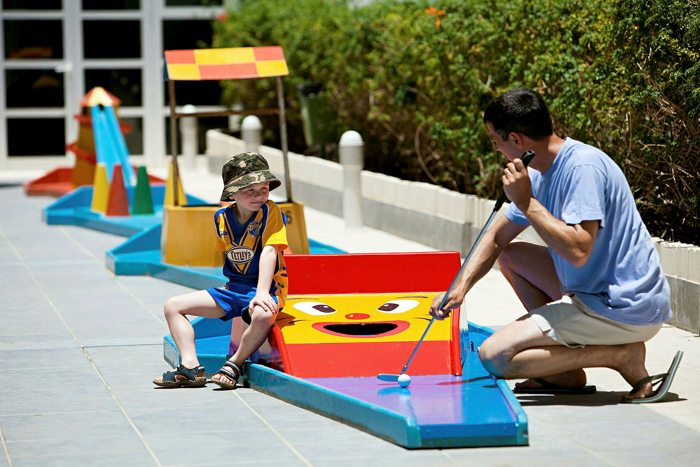Personer spelar minigolf utomhus på en bana med färgglada hinder. (AI-genererad text)