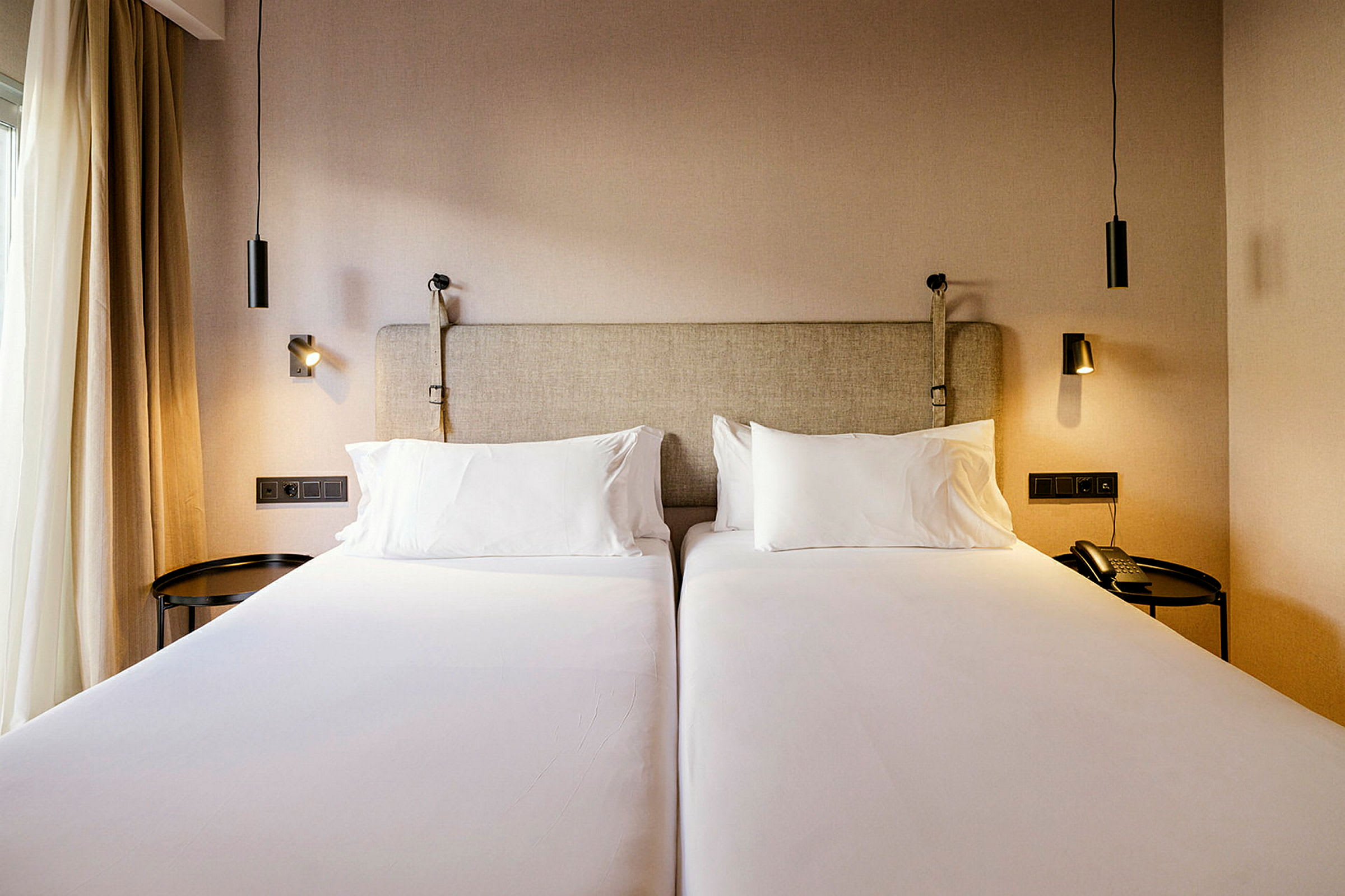 Två enkelsängar i ett hotellrum med sänglampor. (AI-genererad text)