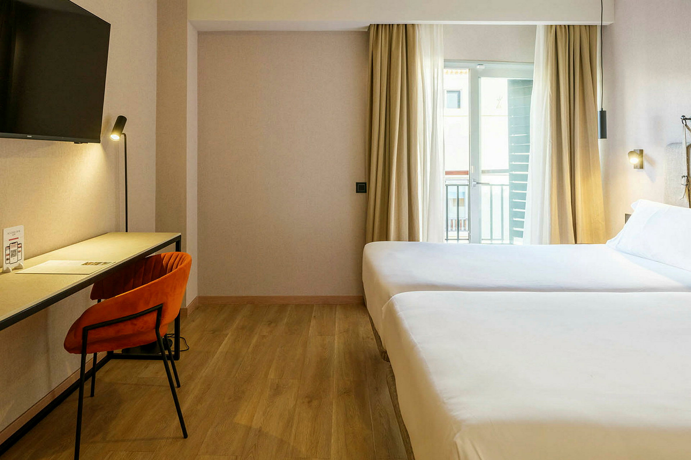 Ett hotellrum med två sängar, skrivbord och stol. (AI-genererad text)