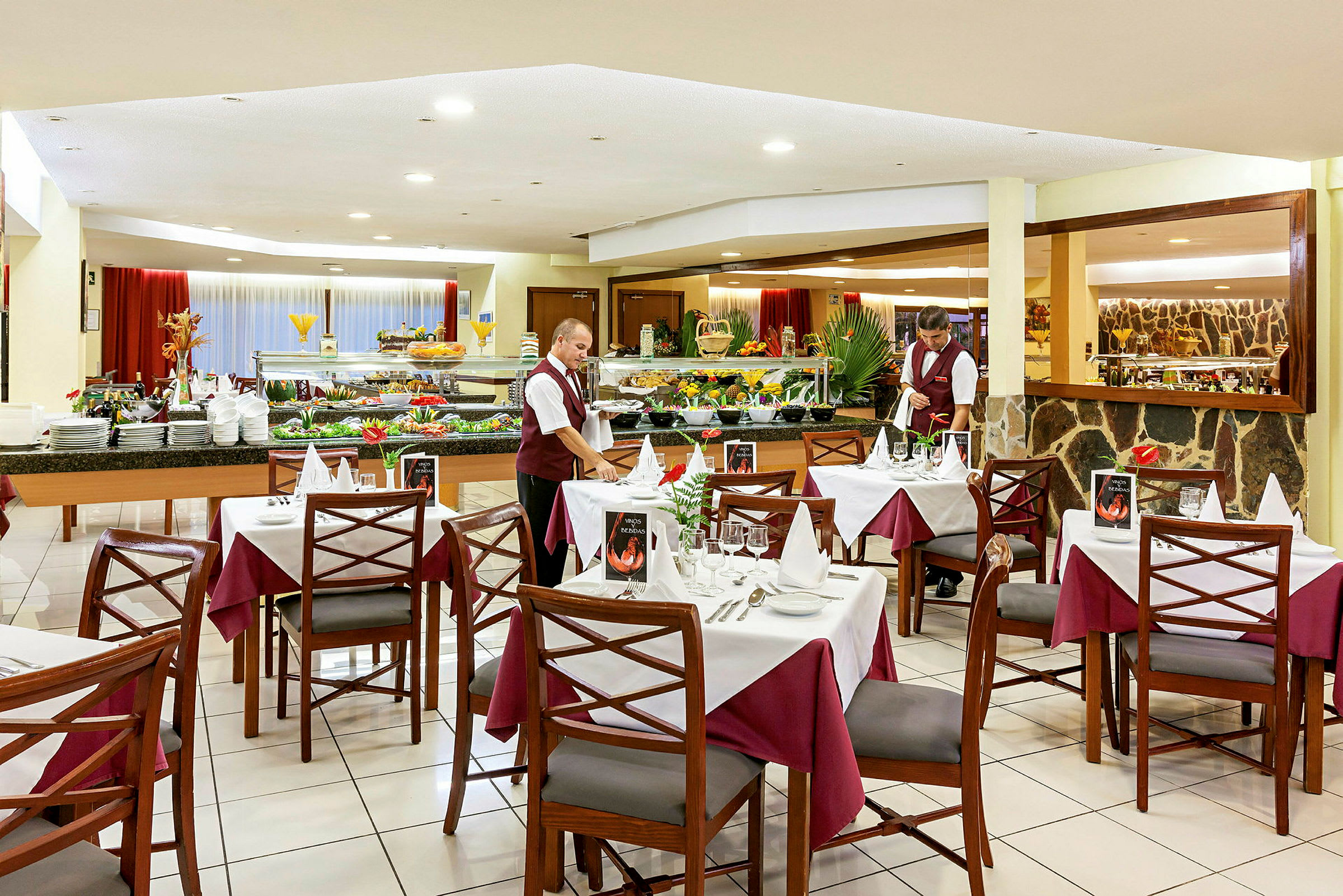 En restaurang med dukade bord, välfyllda bufféer och en servitör klädd i uniform. (AI-genererad text)