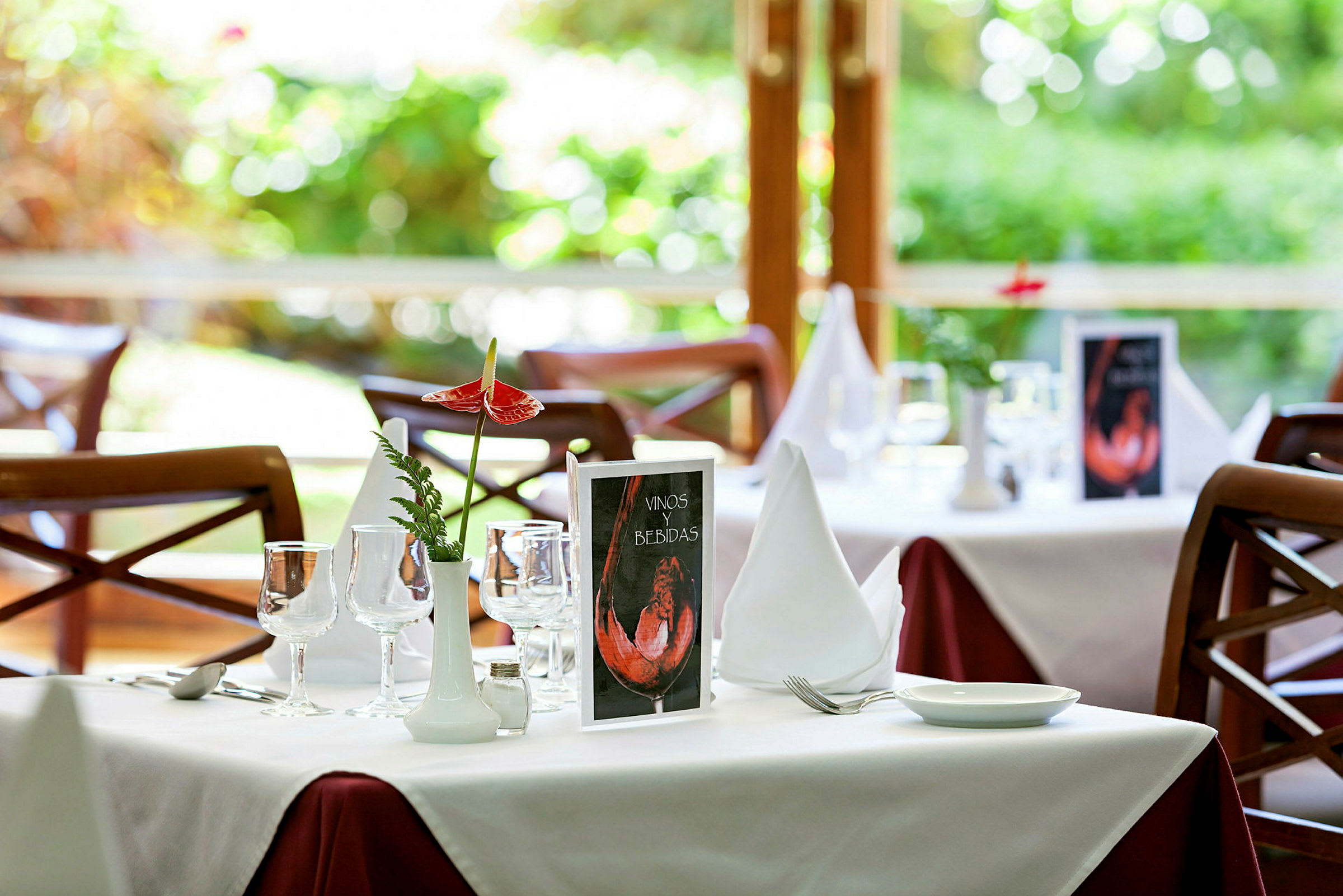 Ett dukat bord i en restaurang med vit bordsduk och dekorationer. (AI-genererad text)