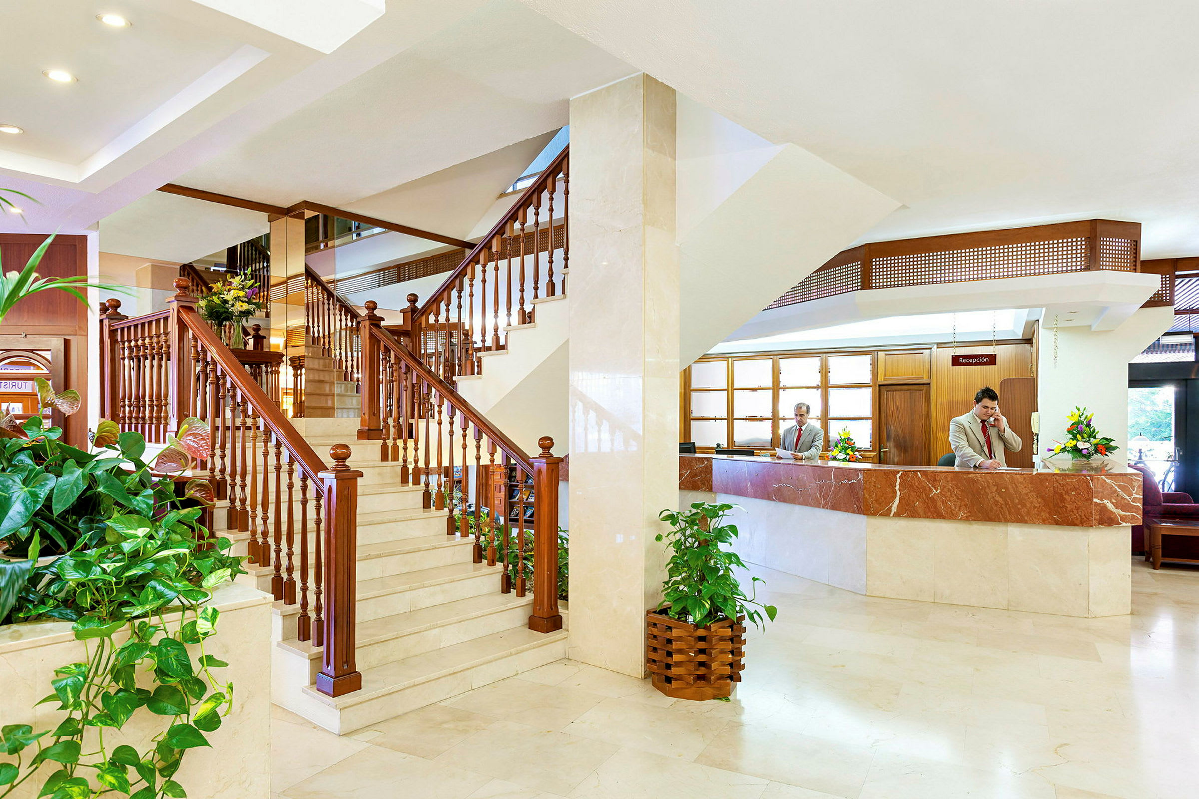 Hotellobby med trappa av trä och reception. (AI-genererad text)