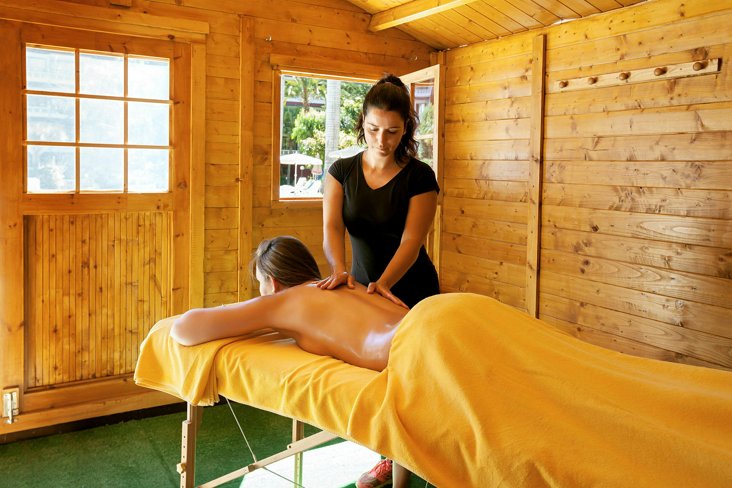 Person får ryggmassage i träbyggnad. (AI-genererad text)