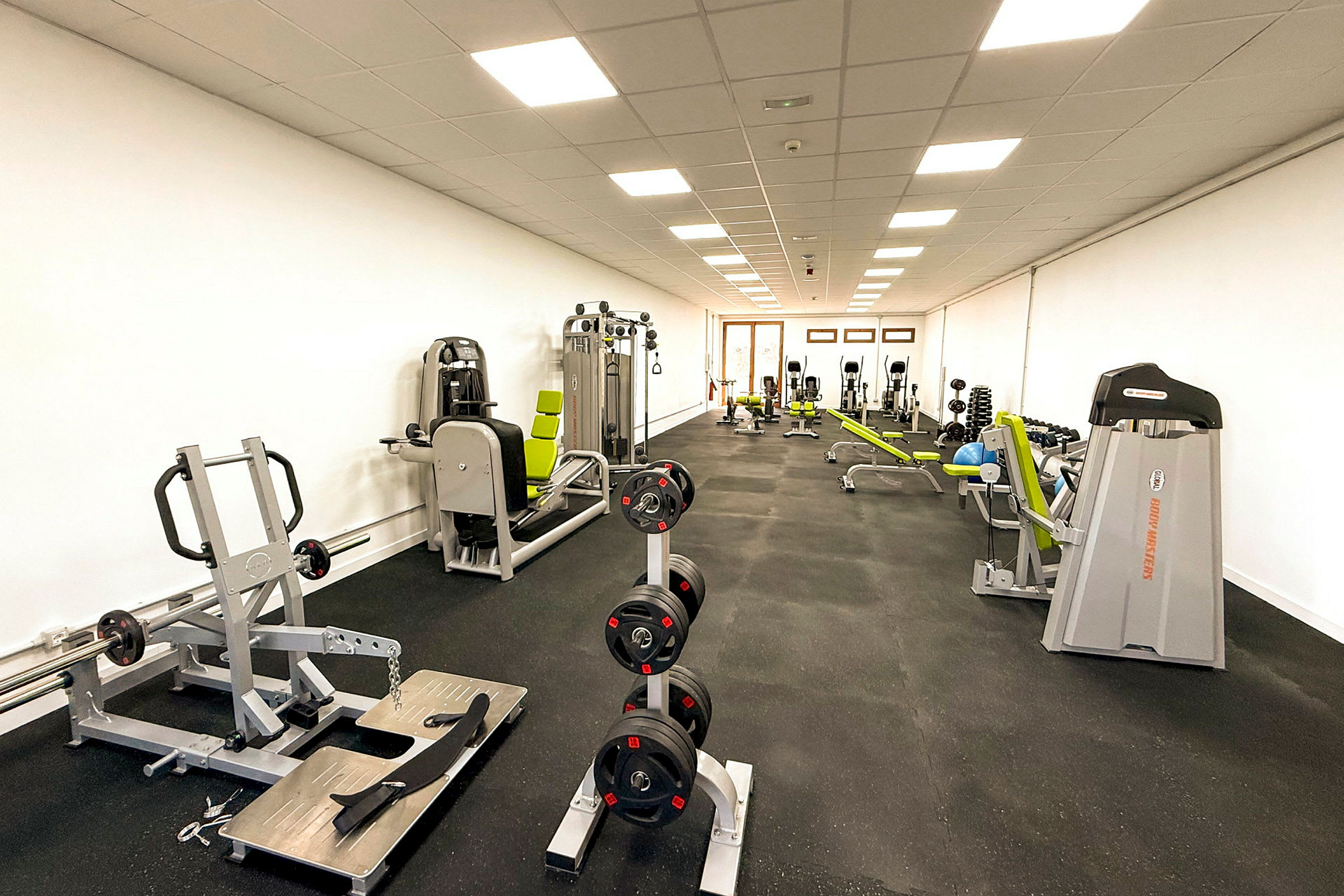 Ett gym med träningsmaskiner och styrketräningsutrustning. (AI-genererad text)
