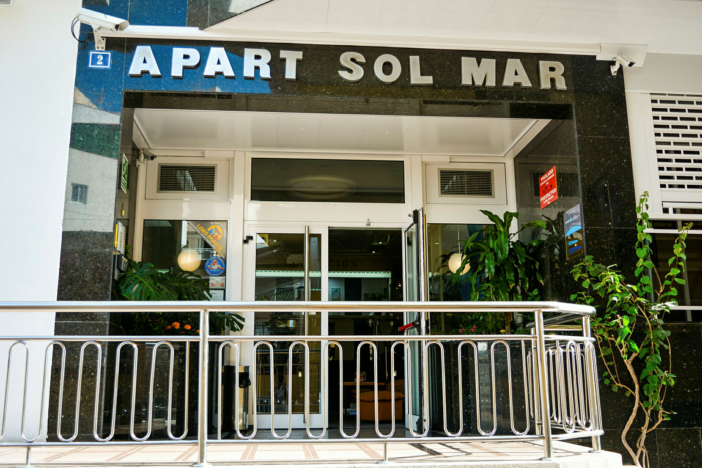 Entré till Apart Sol Mar med glasdörrar och växter. (AI-genererad text)